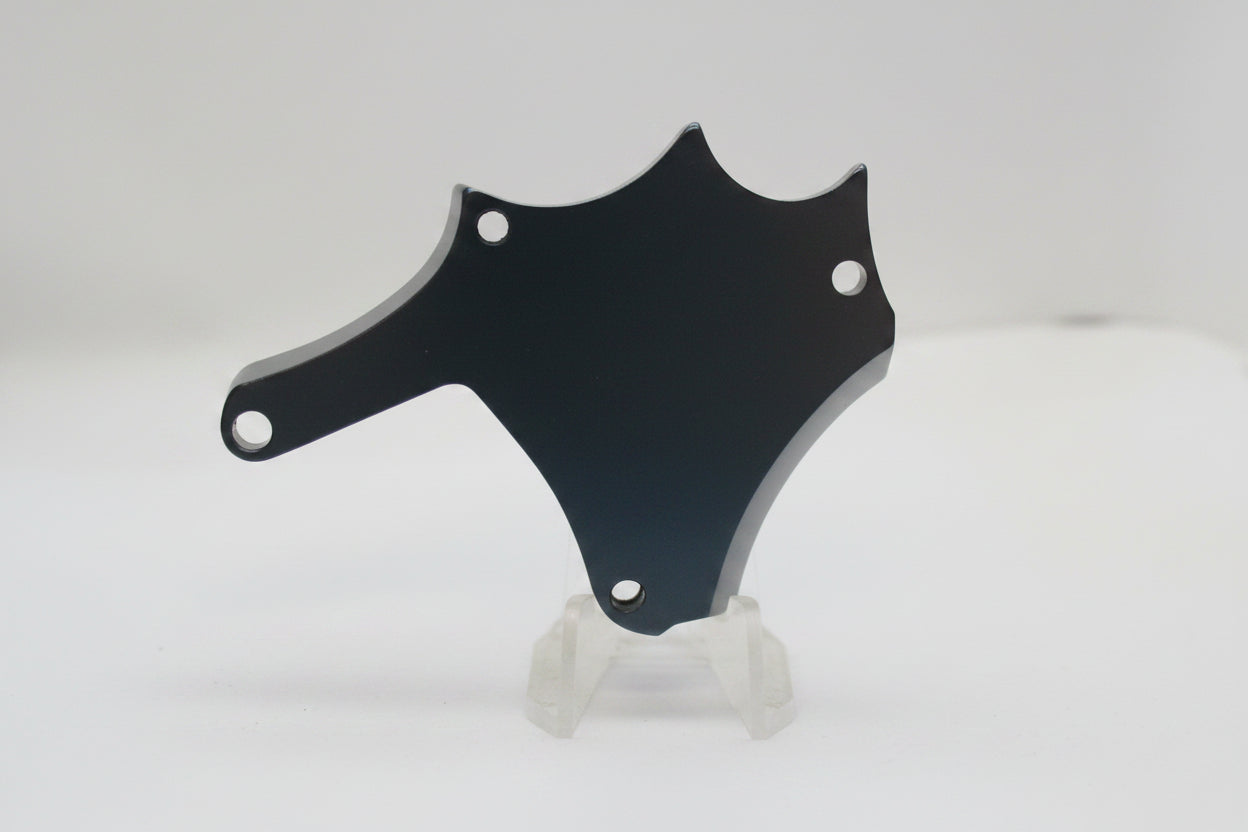 A dark, shield-shaped metal or plastic mounting bracket with two screw holes, displayed on a small white stand against a plain light background.