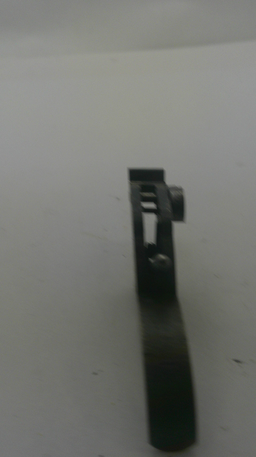 A small black metal hardware component or bracket with a cylindrical knob, shown against a plain off-white background.