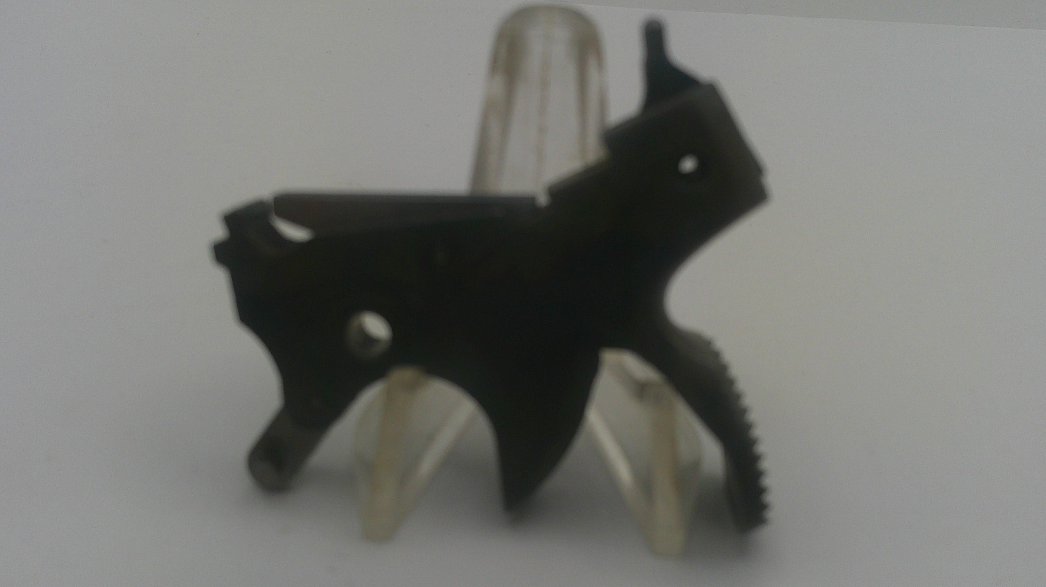 A black metal firearm component, likely a receiver or grip assembly, displayed on a clear plastic stand against a plain light gray background.