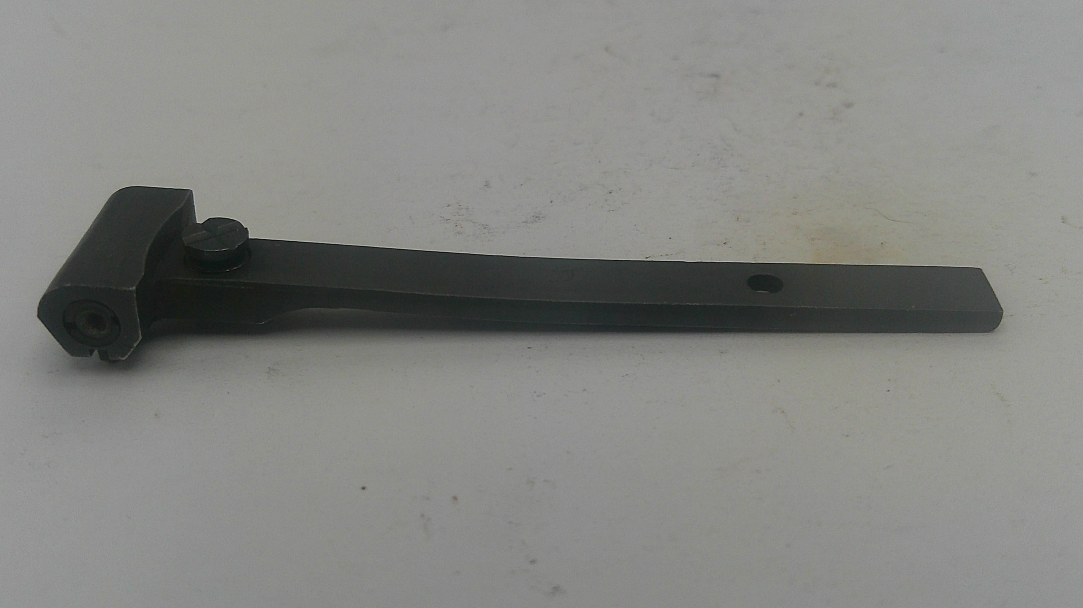 A black metal door lever handle with a mounting bolt and a small adjustment knob, photographed on a light gray surface.