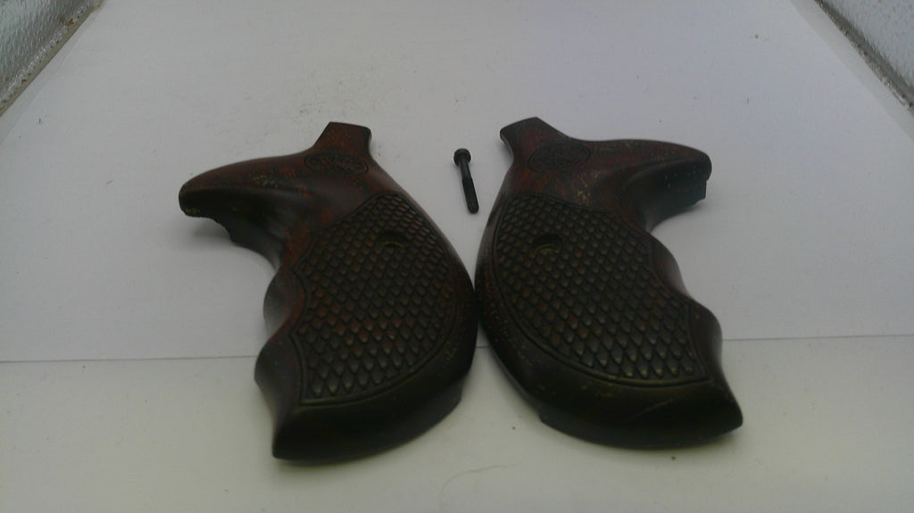 Pair of brown gun grips on a white surface with a screw.