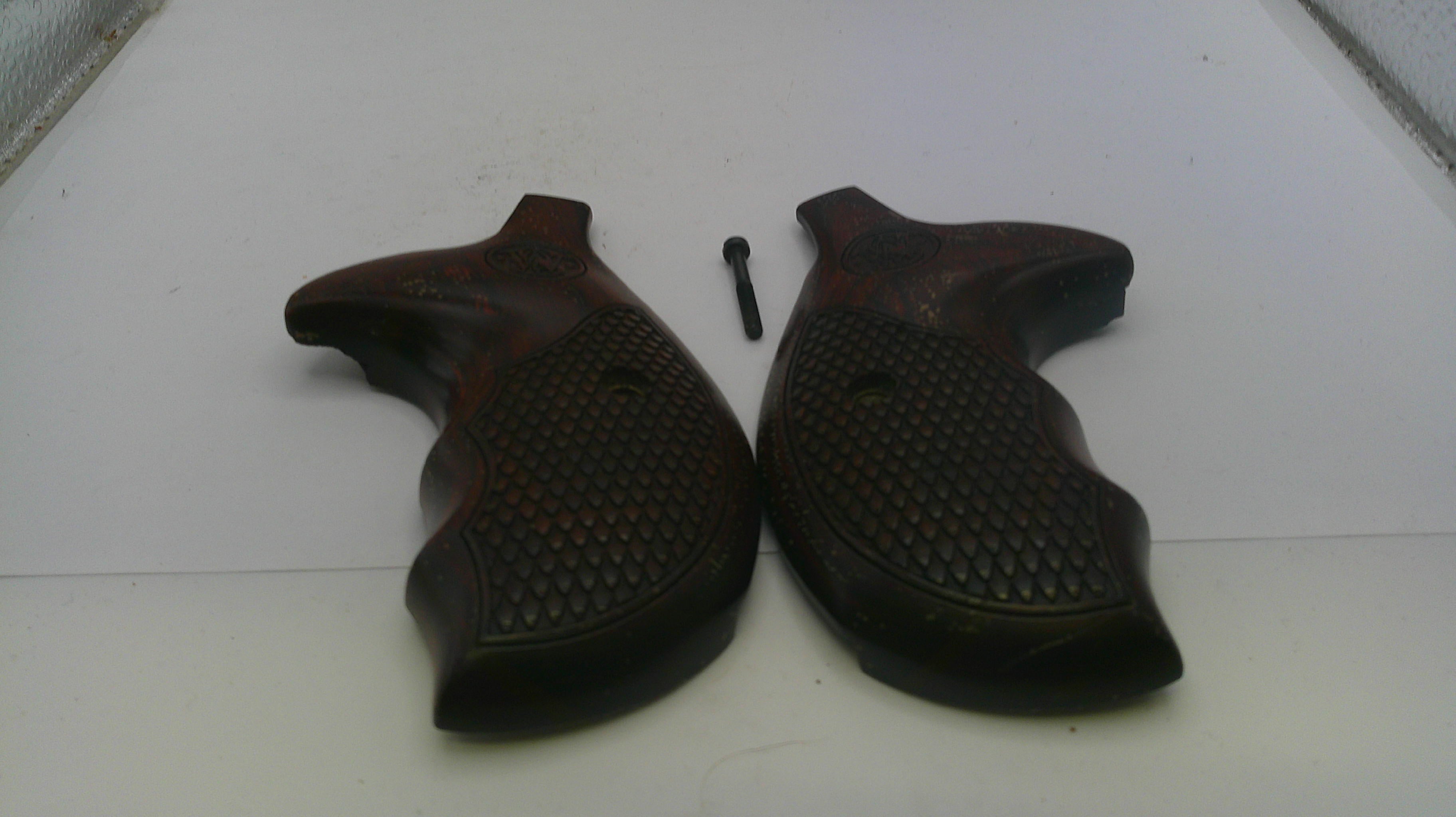 Pair of brown gun grips on a white surface with a screw.