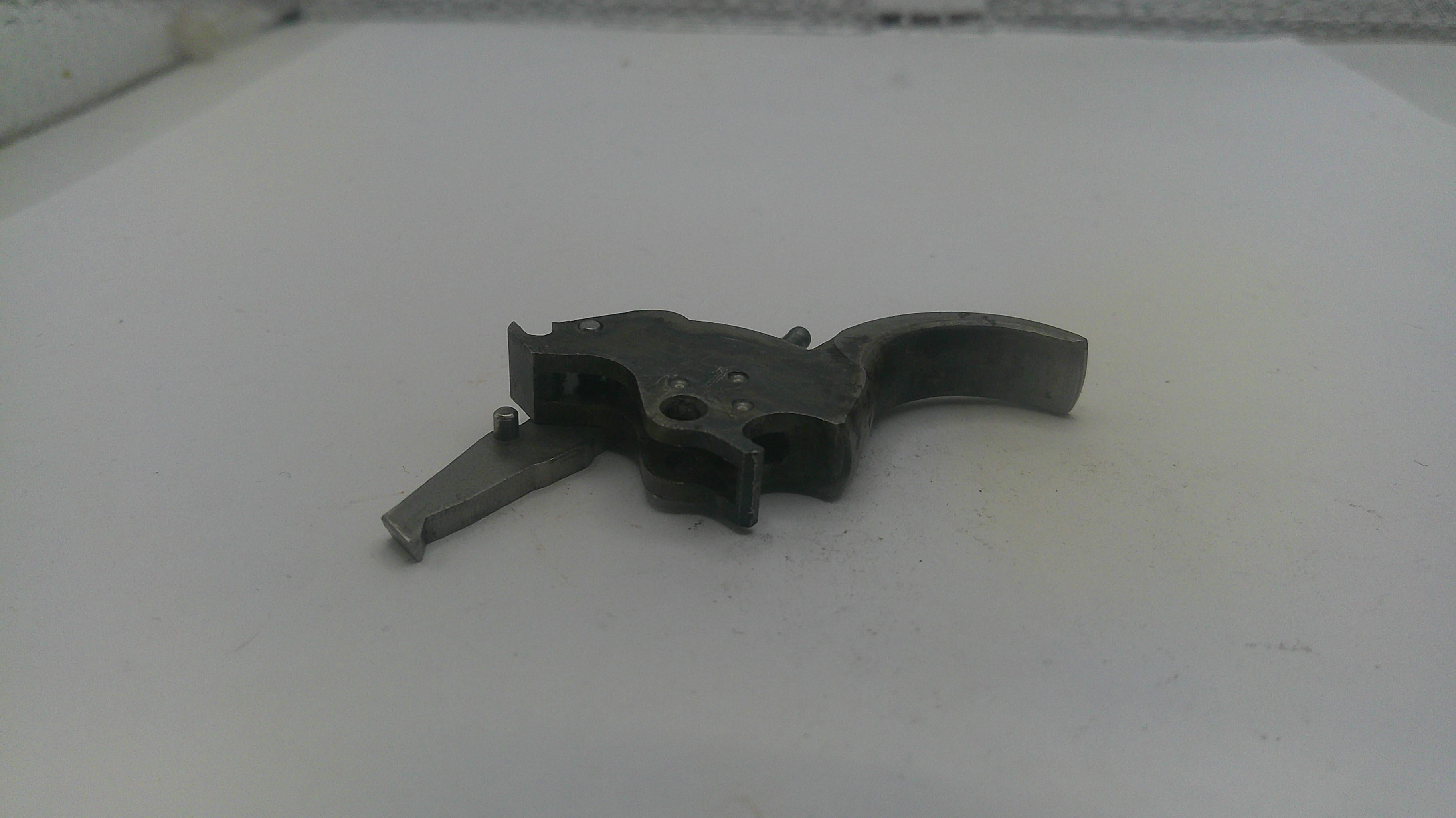 Metallic gun part on a white surface