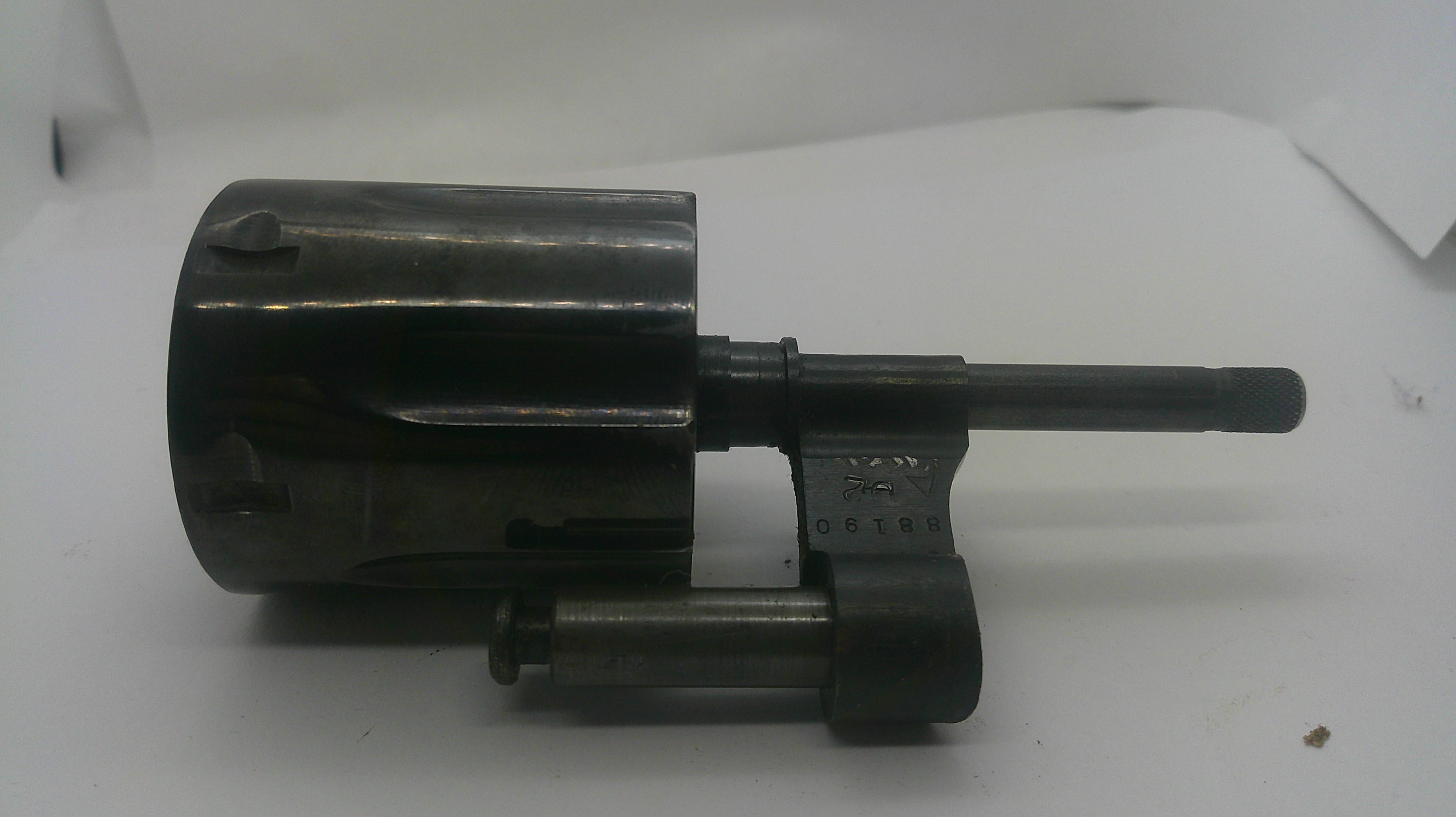 A dark metallic mechanical part, possibly a lock cylinder or tool component, photographed on a plain white background.