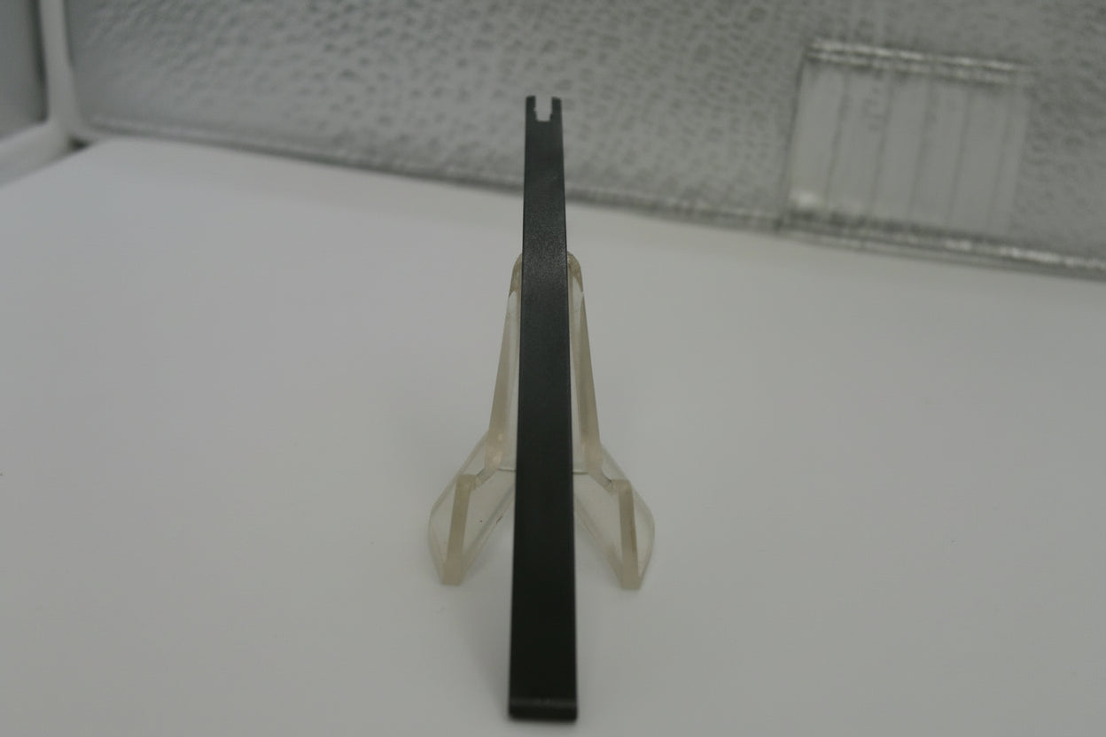 Clear plastic object on a white surface with a textured gray background