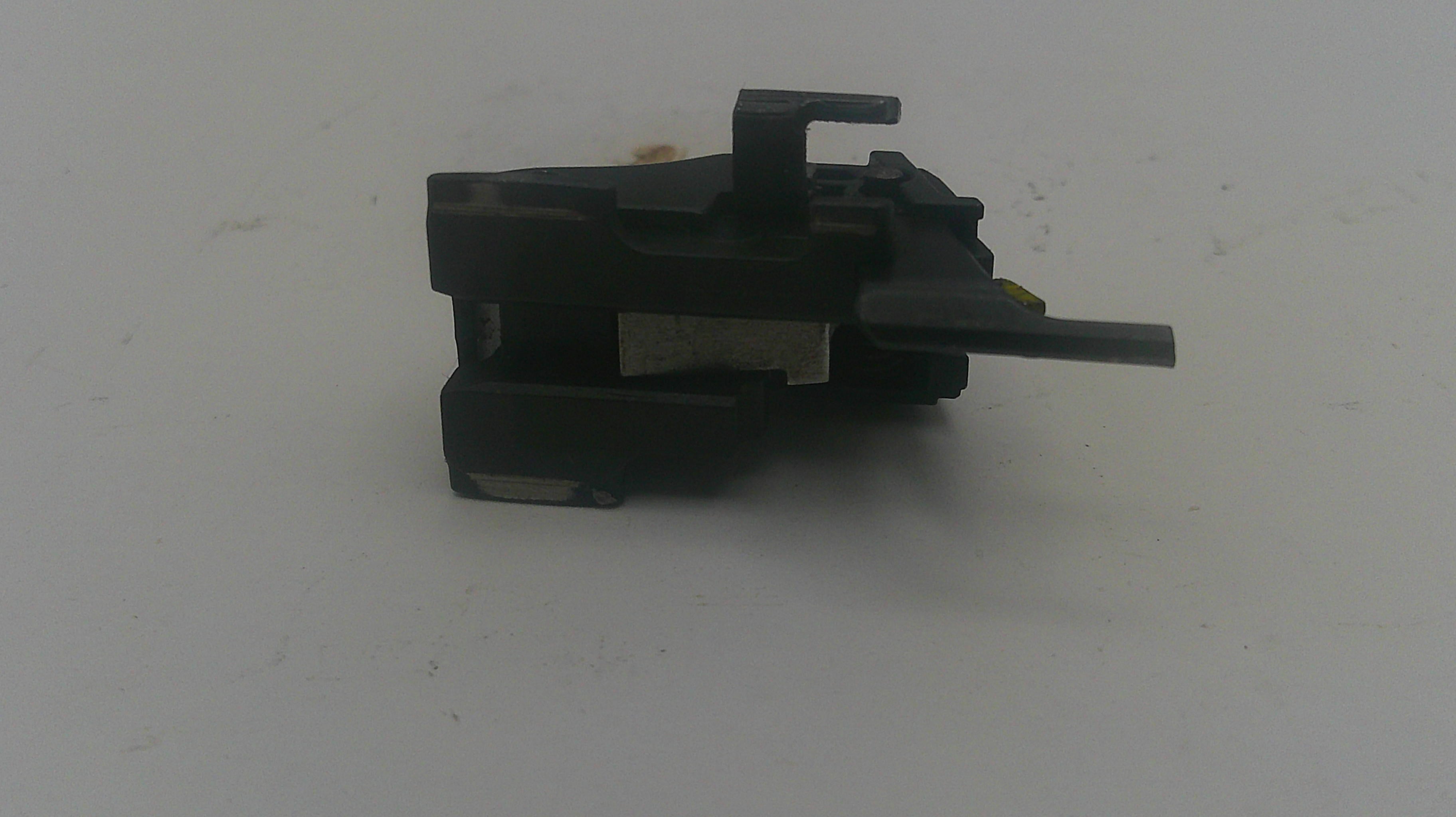 A small black plastic electronic switch or connector component with a short horizontal tab, photographed on a plain light gray surface.