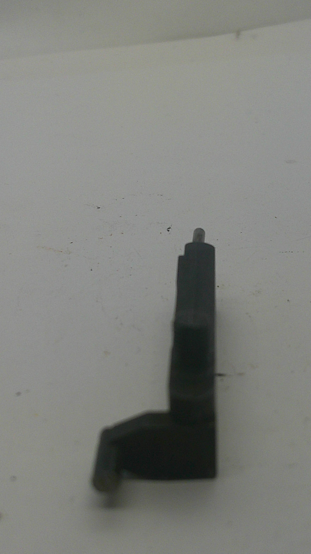 A small black plastic L-shaped component with a metal pin on one end, shown against a plain off-white background.