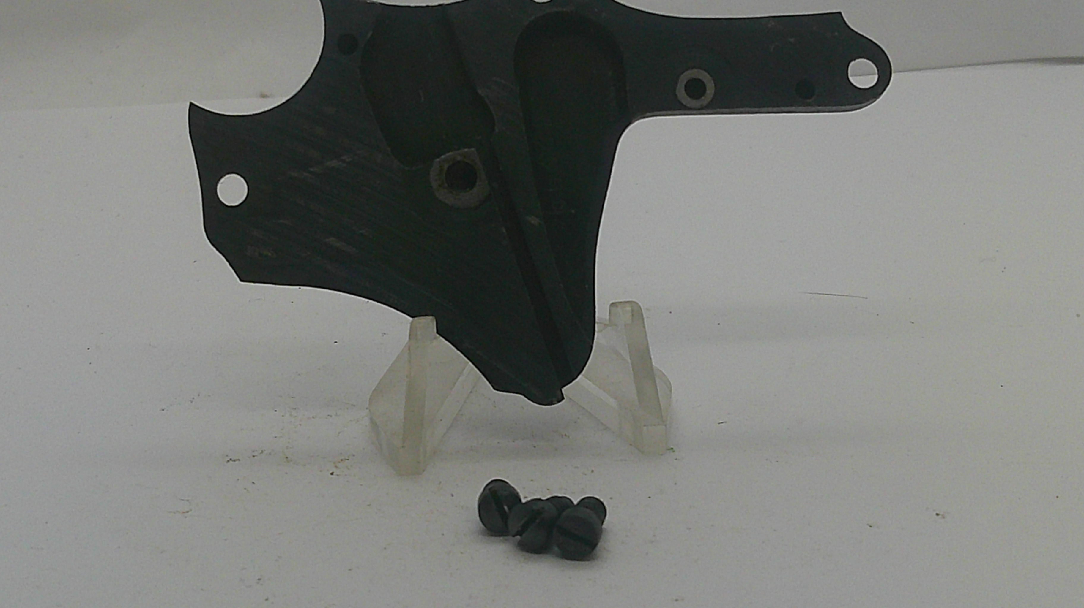 A black plastic motorcycle or bicycle handlebar clamp assembly with mounting holes, displayed on a clear plastic stand with four black screws below, on a white background.