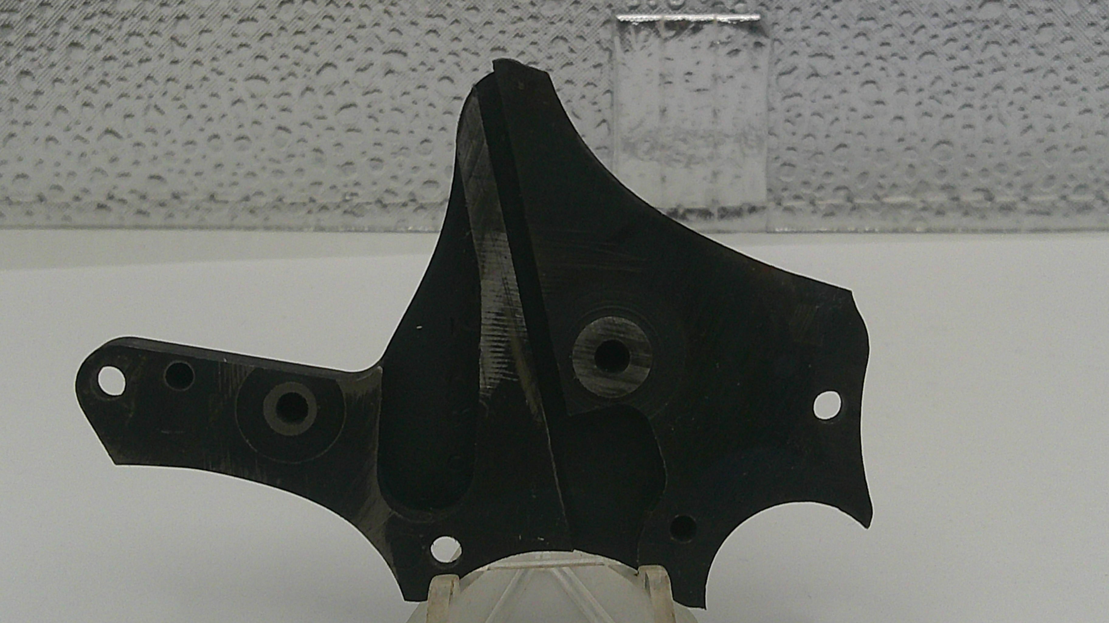 Black metal bracket on a white surface with a textured gray background