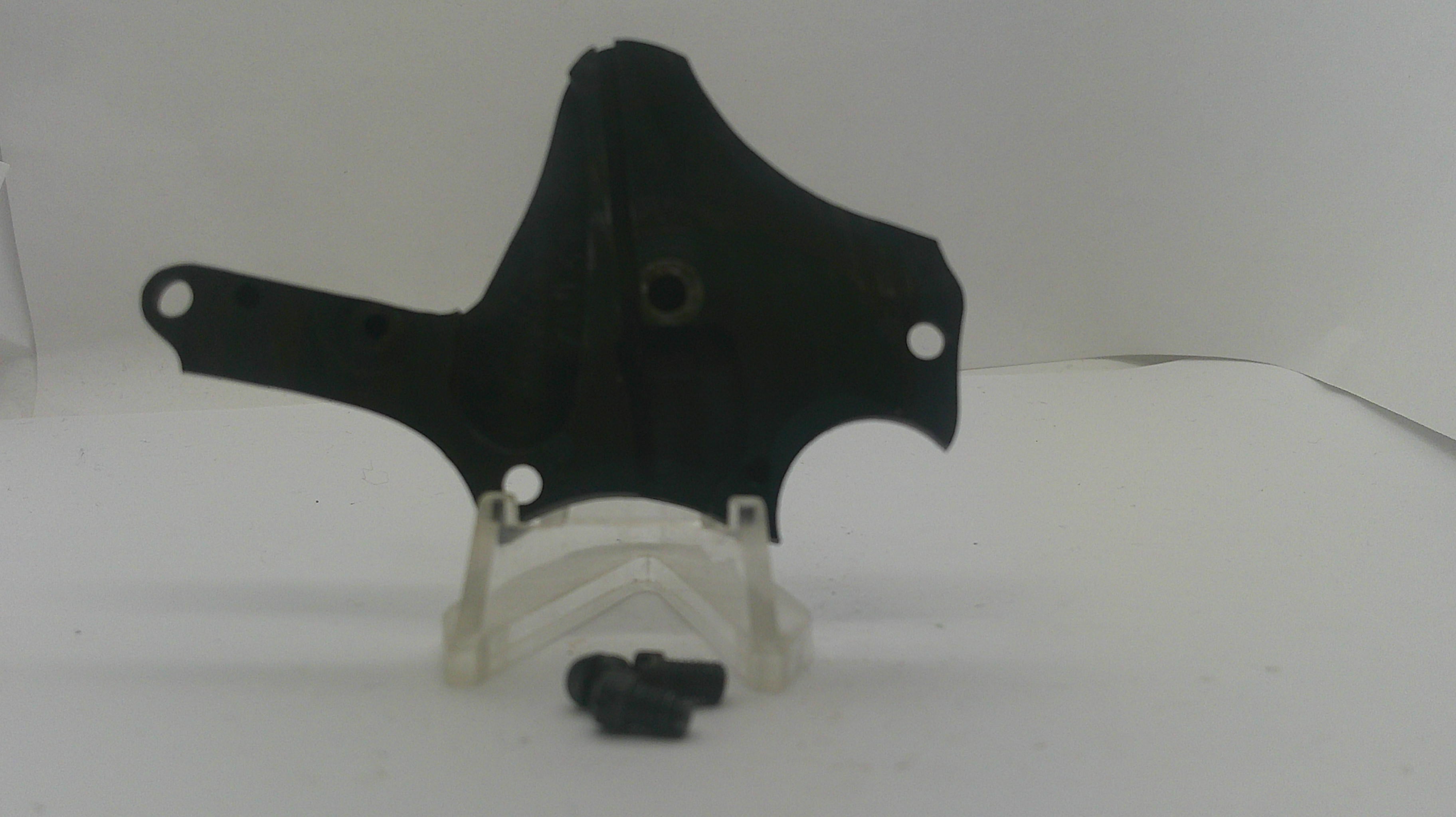 A black plastic mounting bracket or cover with pre-drilled holes, displayed on a clear plastic stand with two small black screws in front, set against a plain white background.