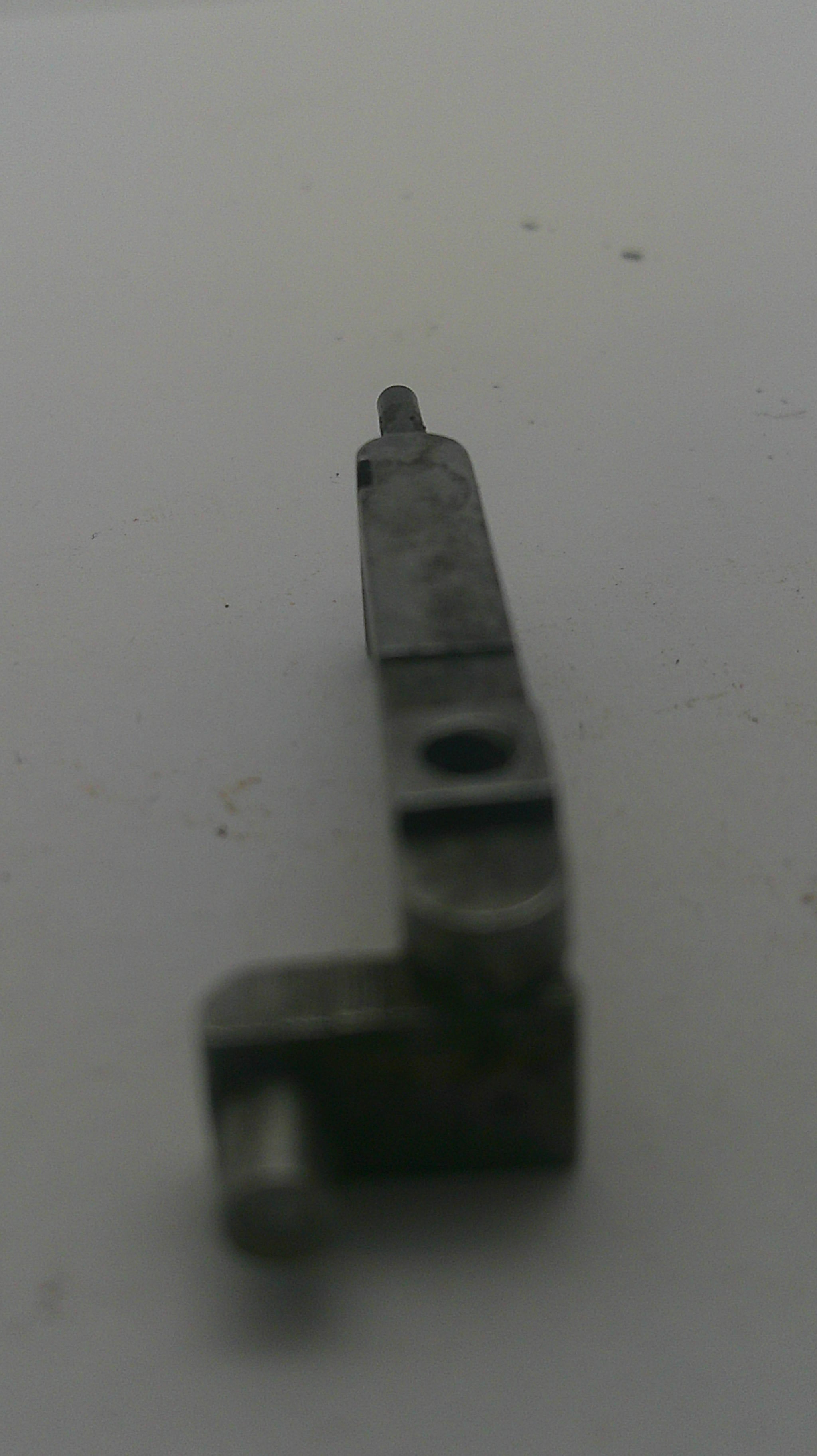 A small dark gray metal mechanical part or bracket with a pointed tip, shown on a plain off-white background.