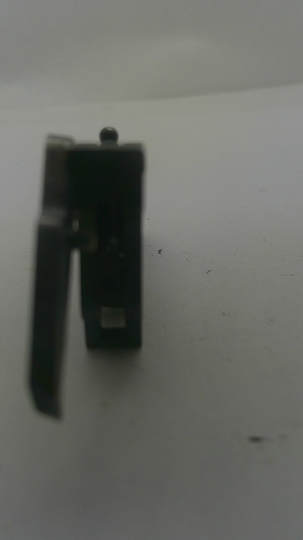 A small black metal hardware component, possibly a latch or bracket, photographed on a plain light background.