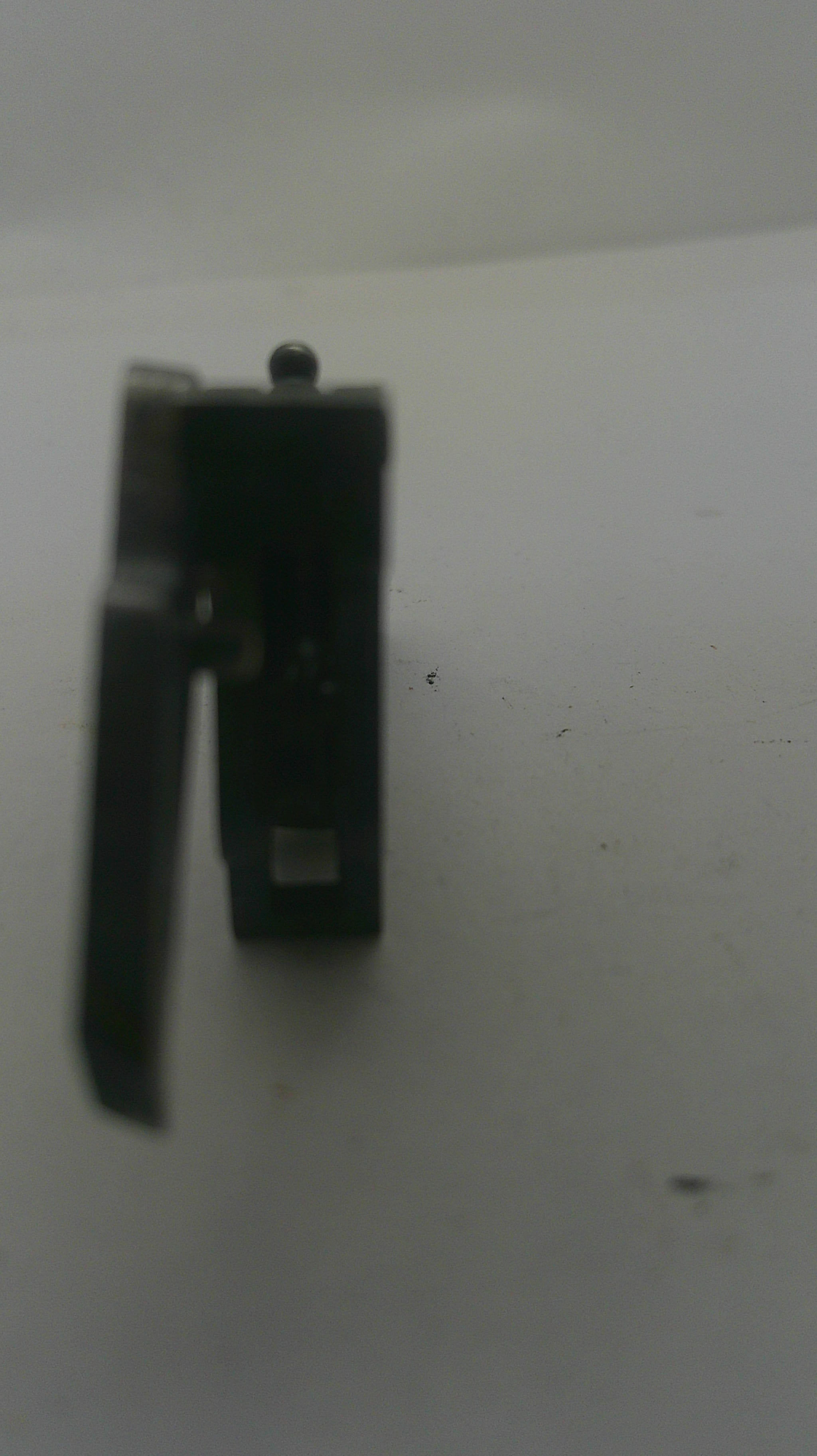 A small black metal hardware component, possibly a latch or bracket, photographed on a plain light background.