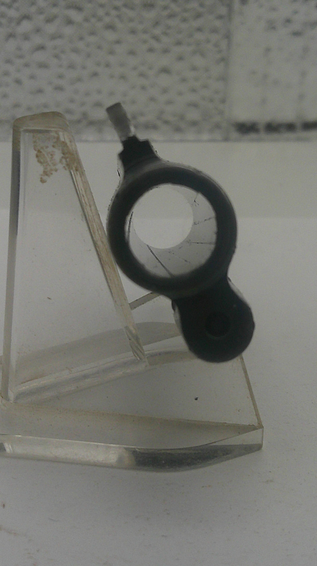 Black rubber gasket on a glass panel with a textured wall background