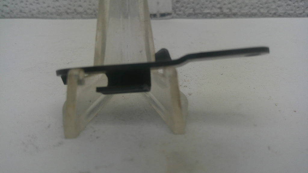 A small black plastic clip or fastener component displayed on a clear plastic stand against a white surface.