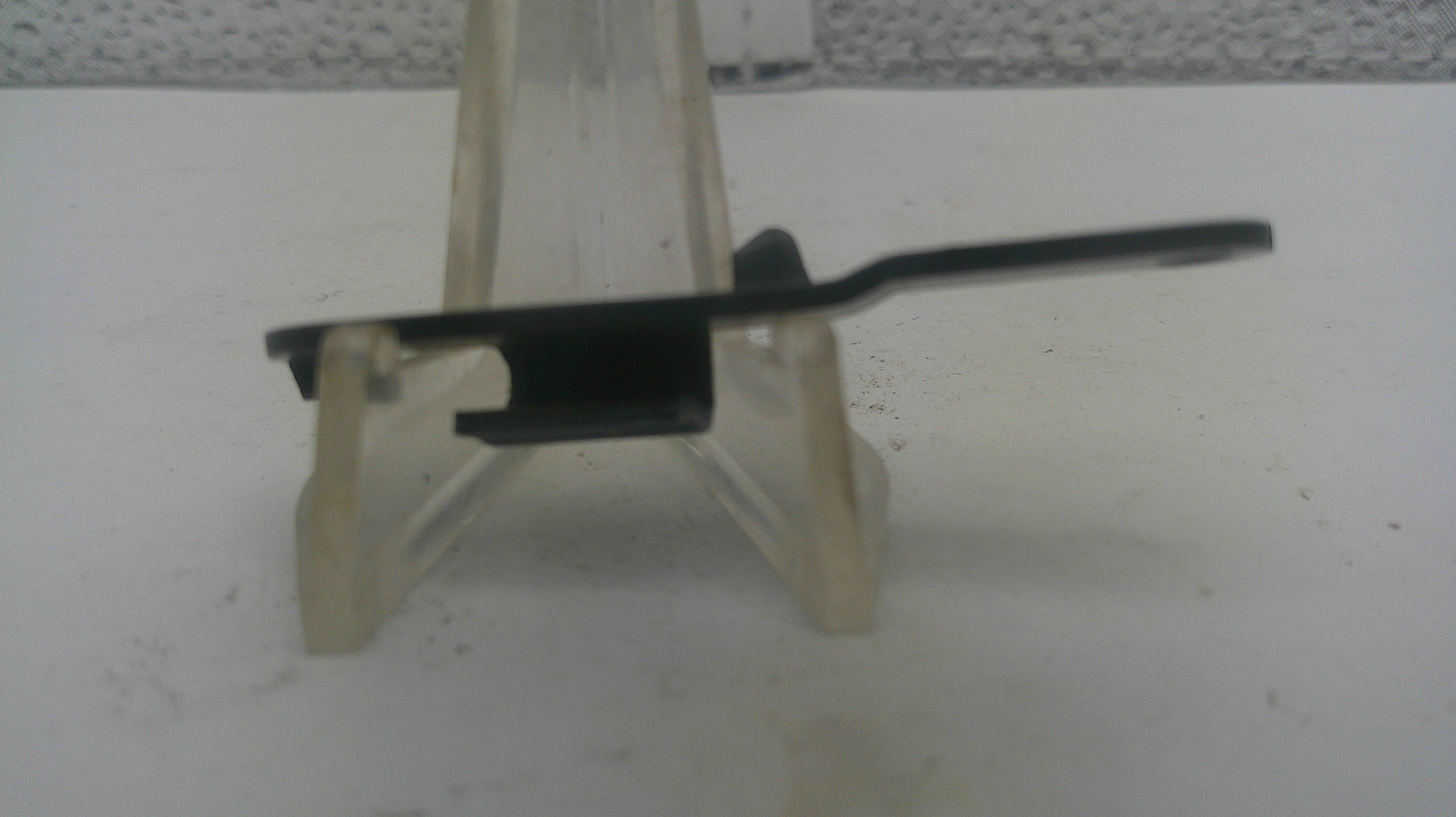 A small black plastic clip or fastener component displayed on a clear plastic stand against a white surface.