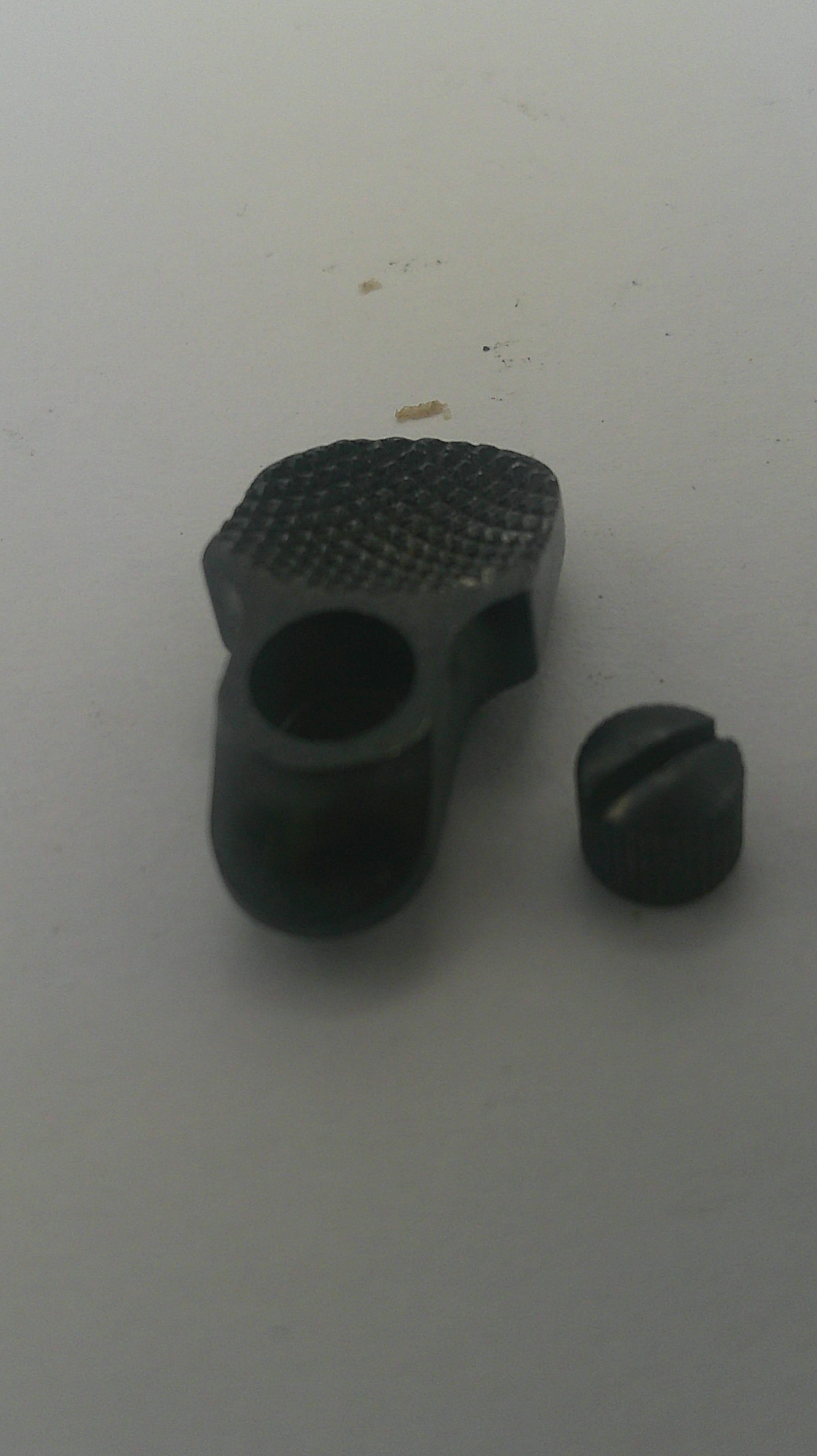 A black textured plastic or rubber cylindrical component with a threaded or knurled end, shown alongside a small matching black cap or cover on a plain light background.