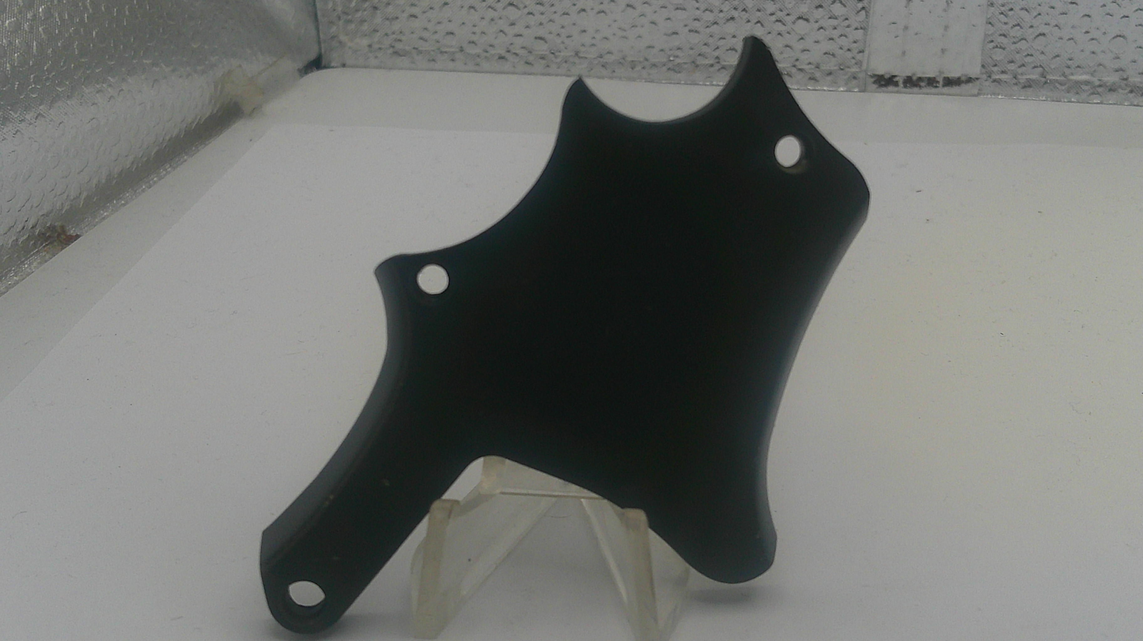 Black motorcycle fender on a white surface with a speckled gray background