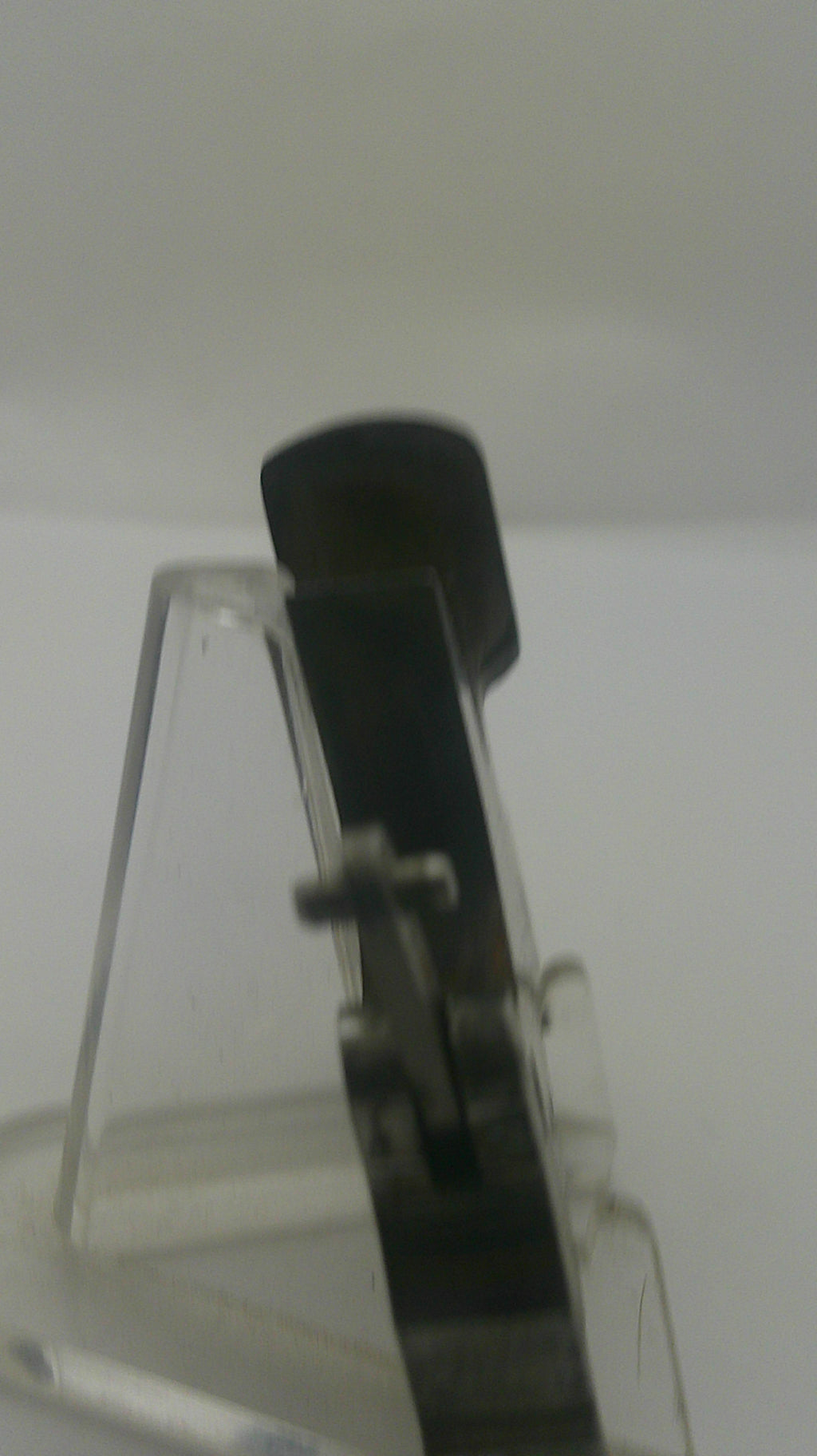 A close-up of a clear plastic clip or fastener component with a black cylindrical section, shown against a plain light background.