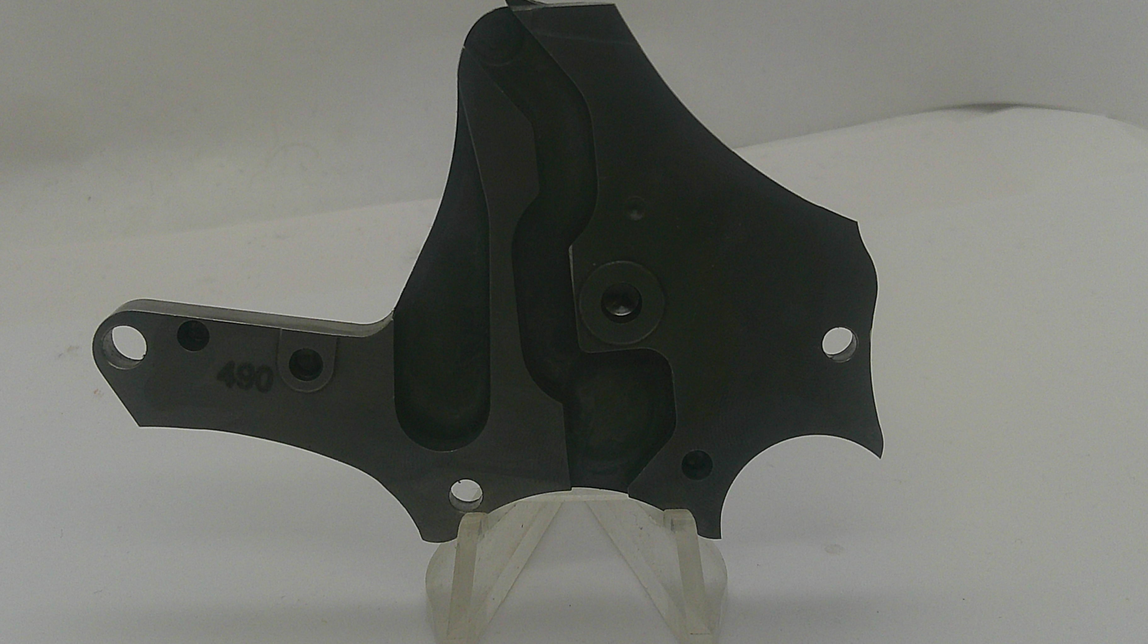 A black metal mechanical bracket or plate with pre-drilled mounting holes, displayed on a clear plastic stand against a white background.