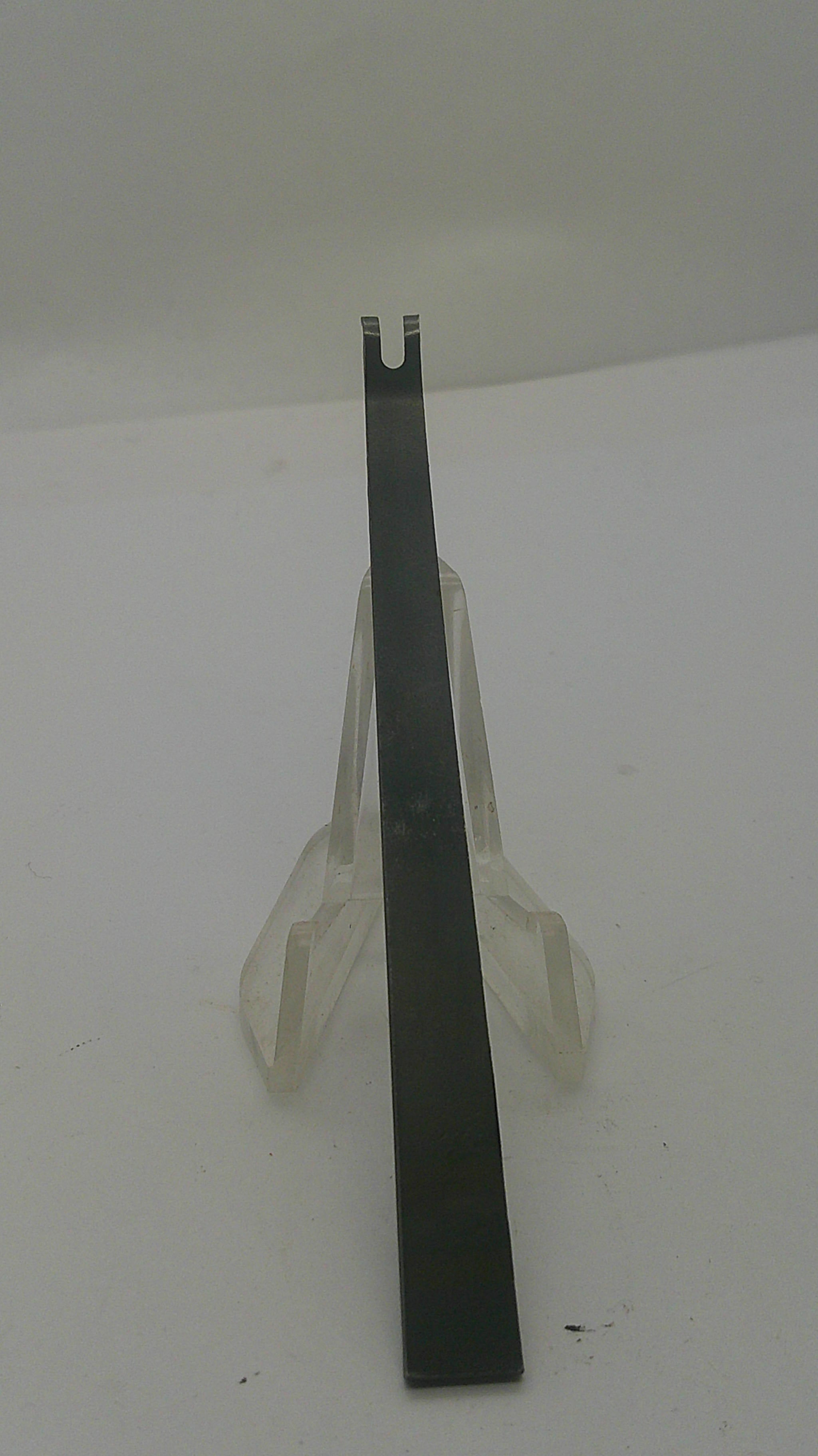 A flat metal pry bar tool with a double-pronged tip, resting on a clear plastic display stand against a plain white background.