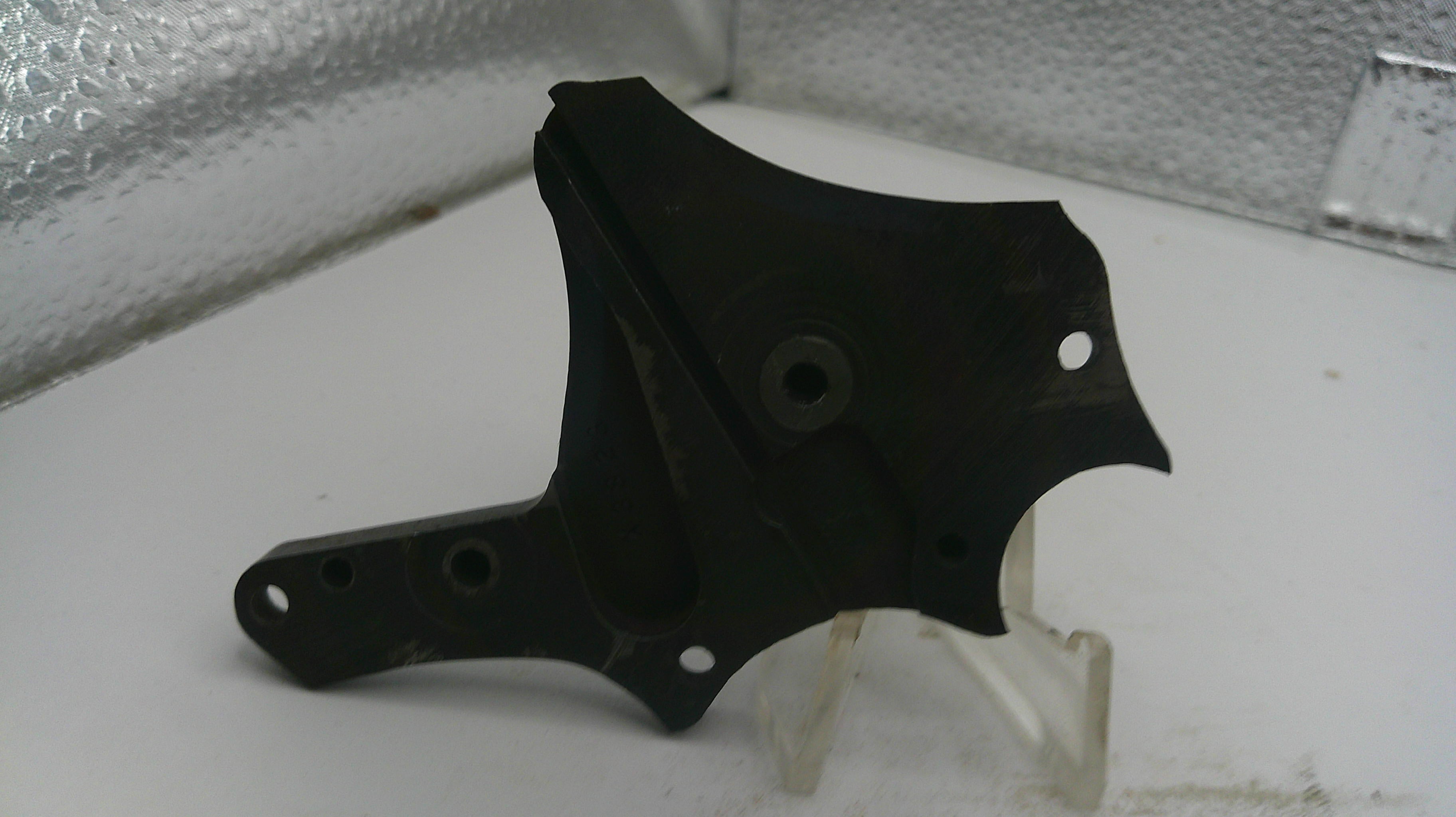 Black metal bracket on a white surface with a reflective background