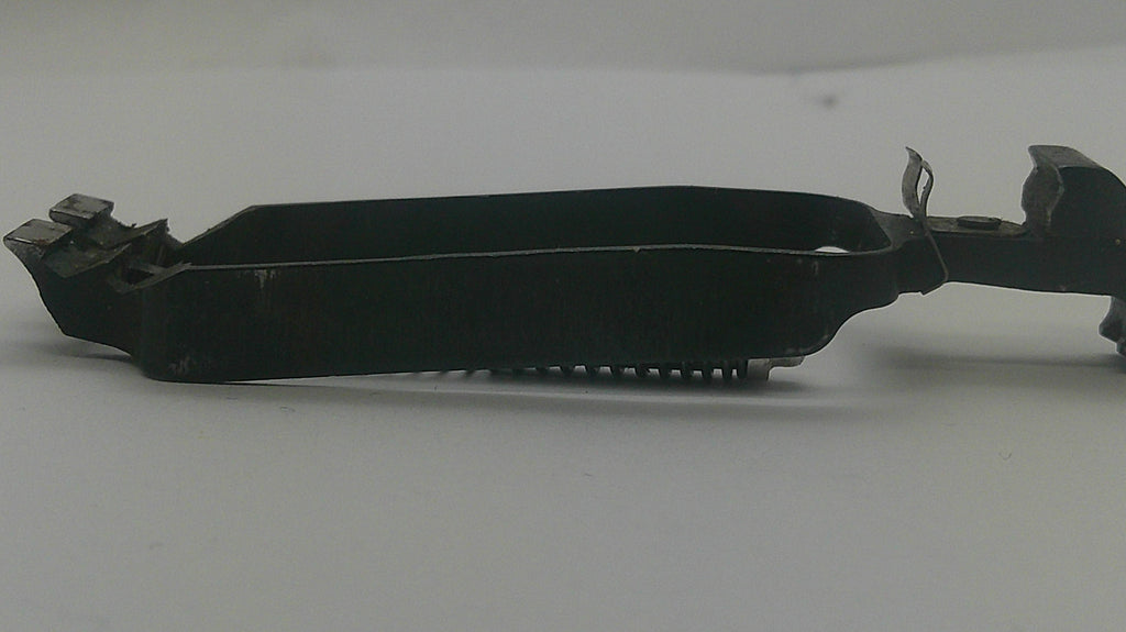 A black metal mechanical component or bracket with a rectangular opening and small protruding teeth on one end, shown on a plain light gray background.