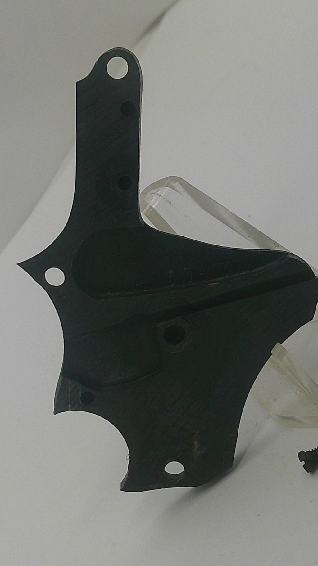 A black molded plastic mounting bracket or cover with pre-drilled screw holes, resting on a white background.