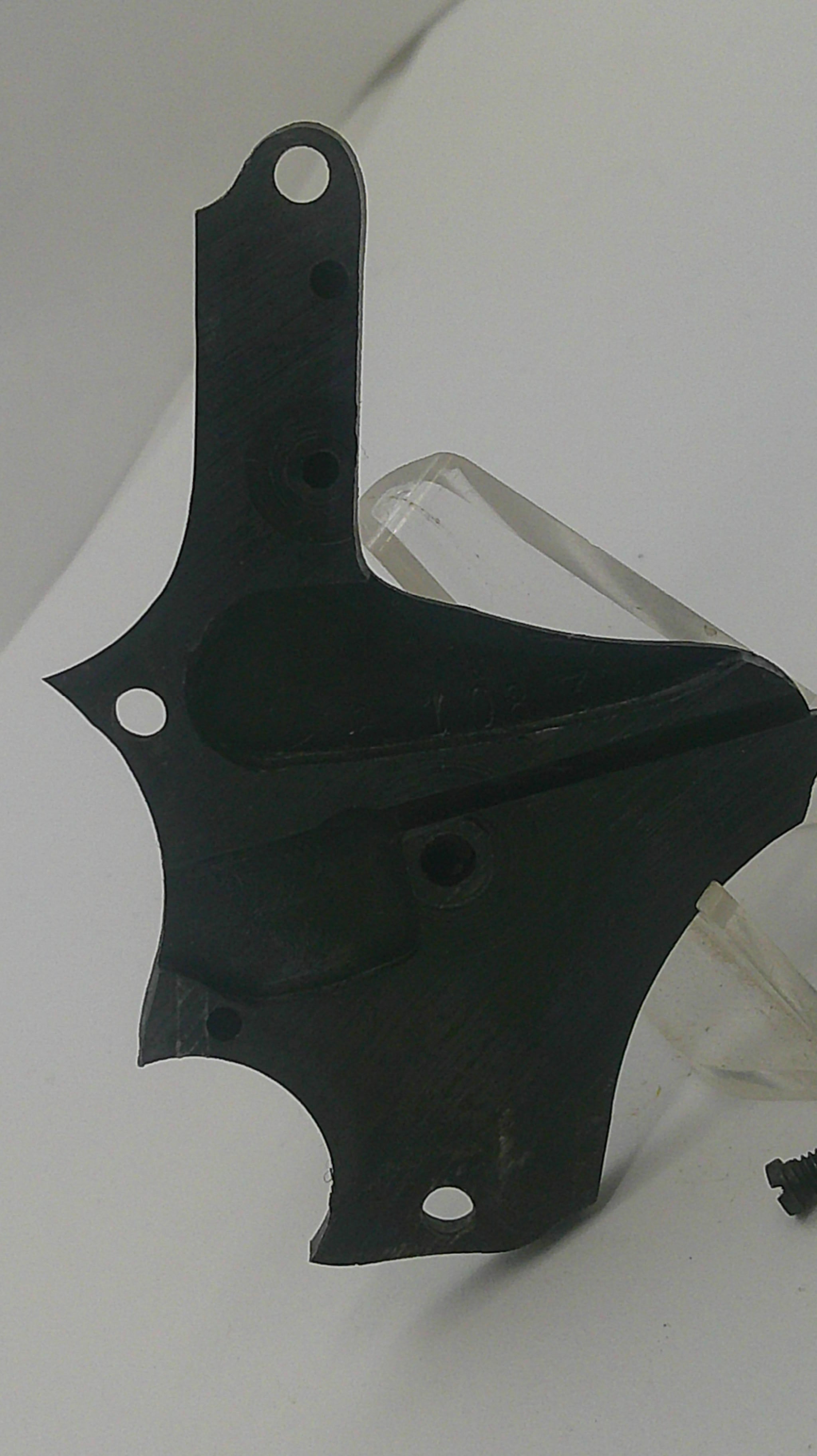 A black molded plastic mounting bracket or cover with pre-drilled screw holes, resting on a white background.