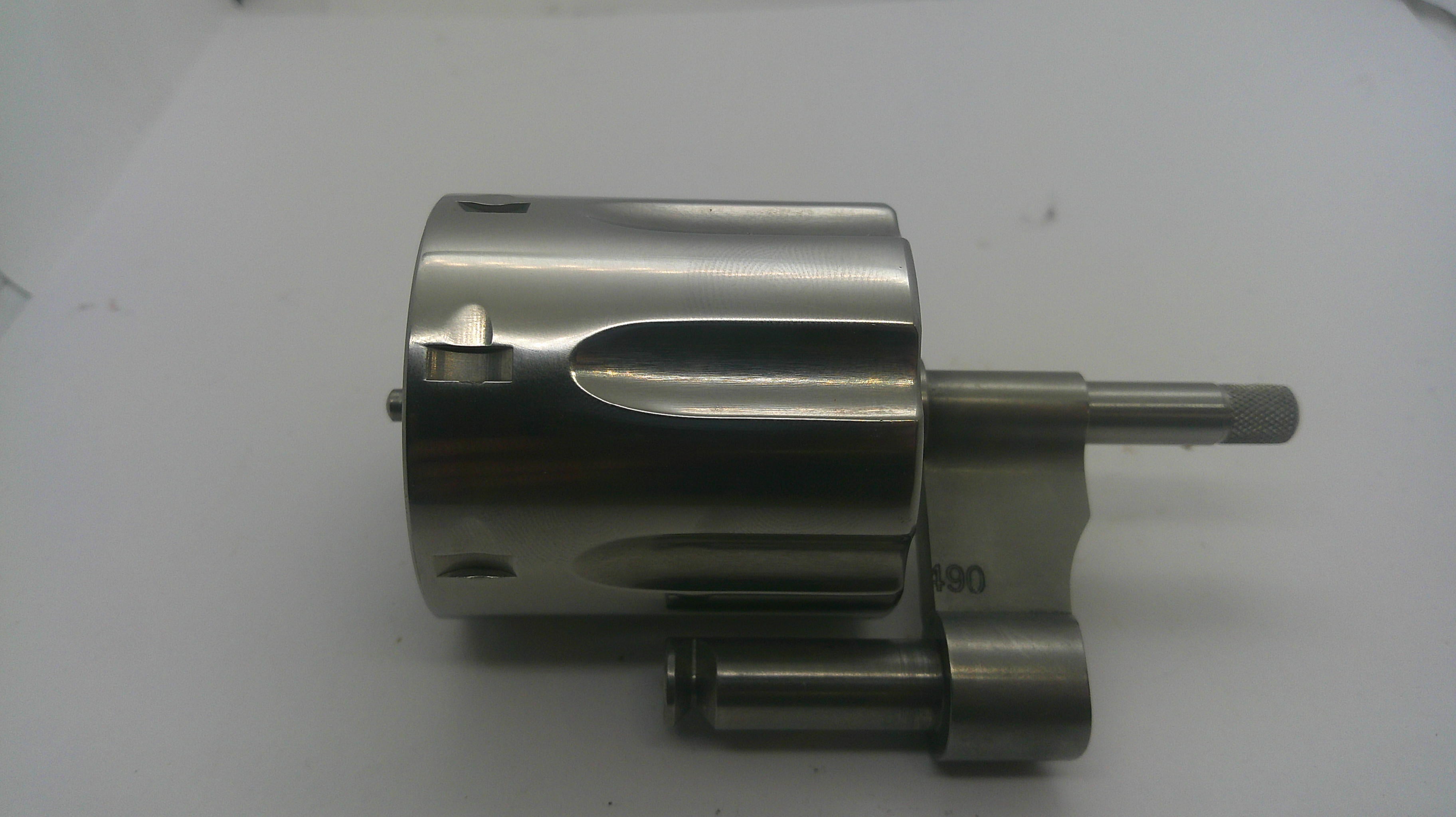 A metallic cylindrical mechanical component with a polished silver finish, featuring a protruding shaft and mounting bracket, photographed on a plain light background.