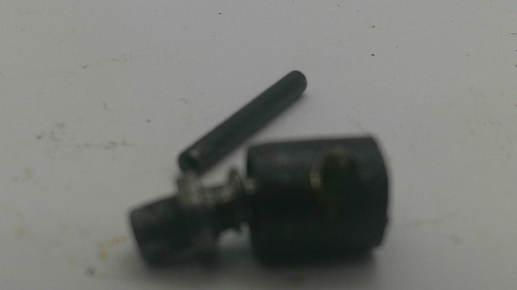 A small black metal mechanical component with a cylindrical body and a separate matching pin, photographed on a plain off-white surface.
