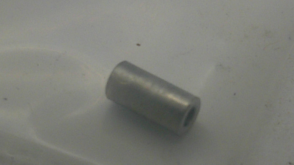 A small metallic silver cylindrical bead with a hollow center, resting on a light gray surface.