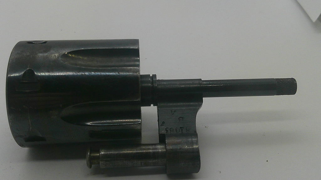 A used dark gray metal mechanical component, possibly a valve or pump part, with a cylindrical body, a long horizontal rod, and a smaller vertical rod, photographed on a plain white surface.