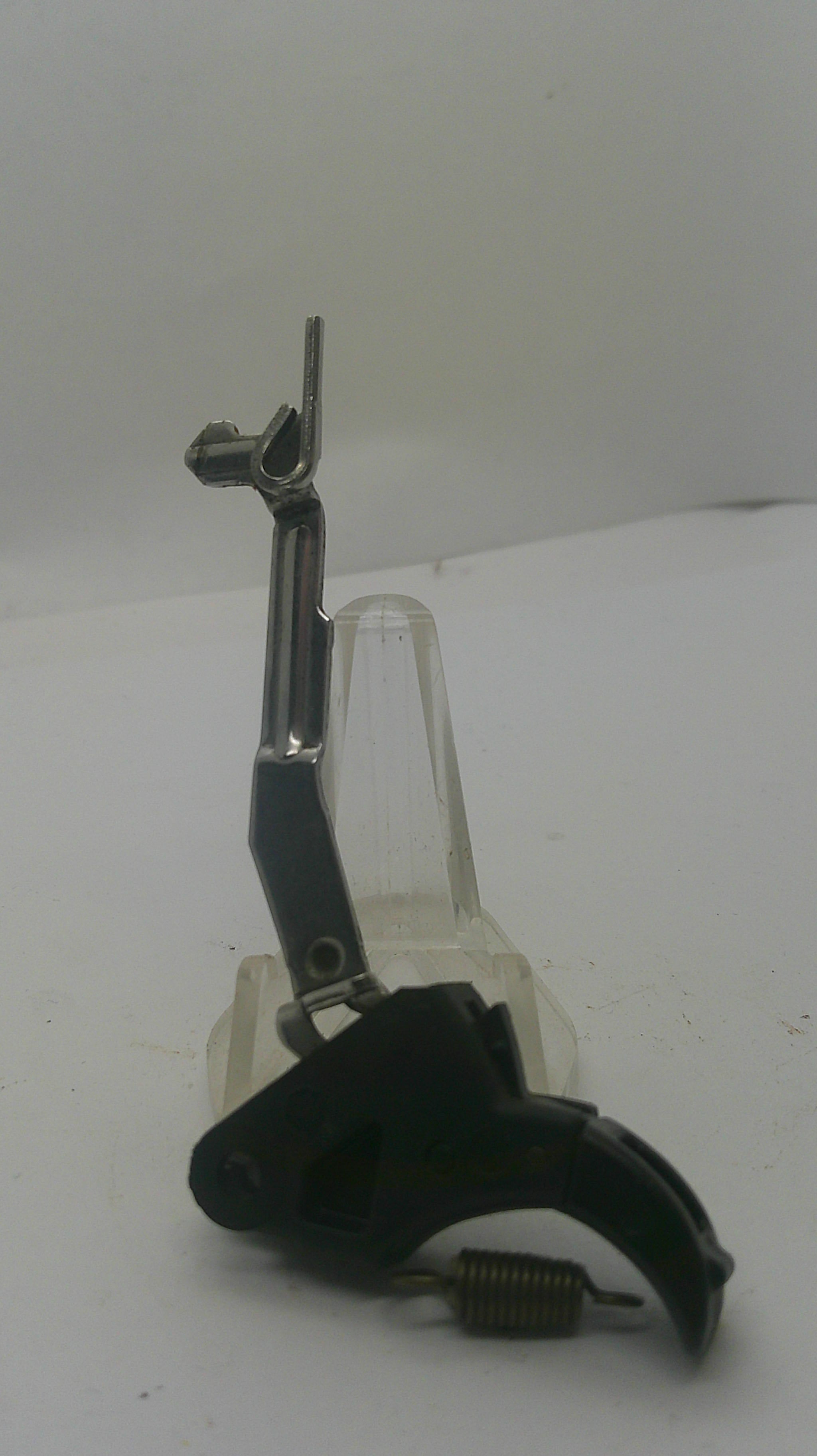 A replacement firearm trigger assembly with a black pistol grip, black safety switch, silver metal barrel shank, and clear plastic guard, shown against a plain white background.
