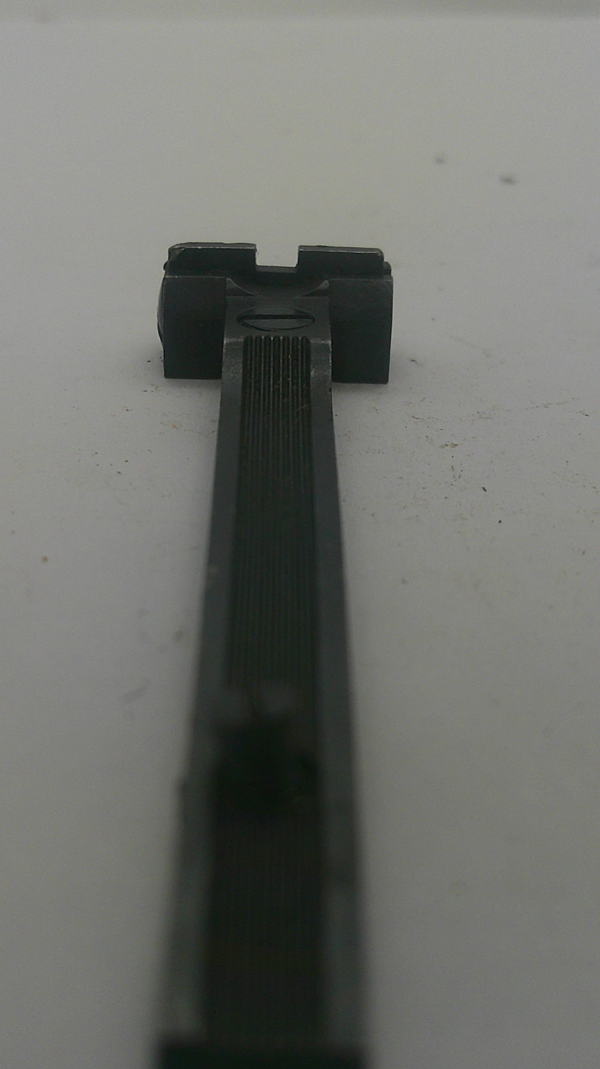 A close-up of a black plastic mounting bracket or clip attached to a white surface.