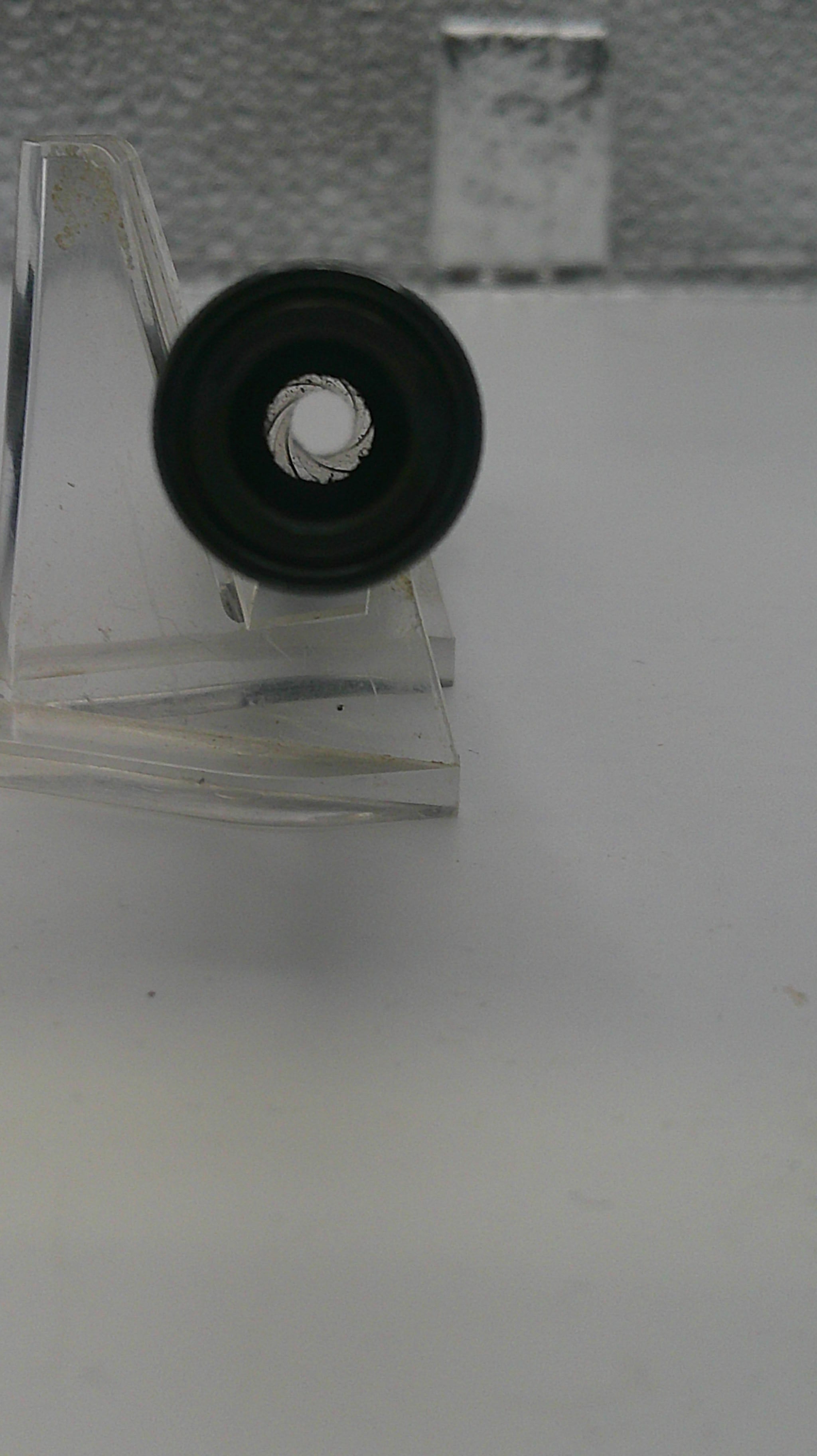 Close-up of a metallic object with a circular component on a white background