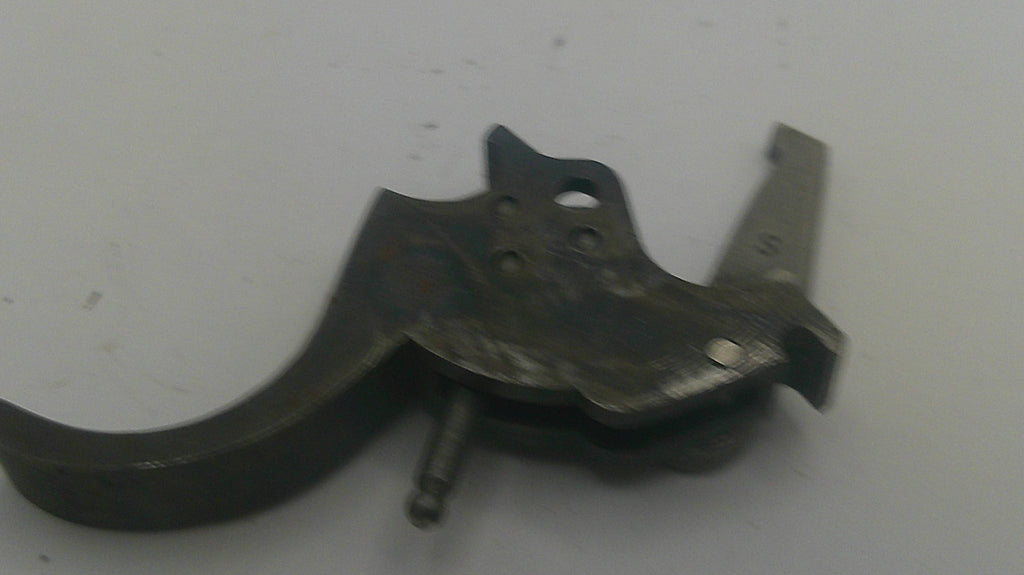 A dark metal firearm trigger assembly component, photographed on a plain light gray background.
