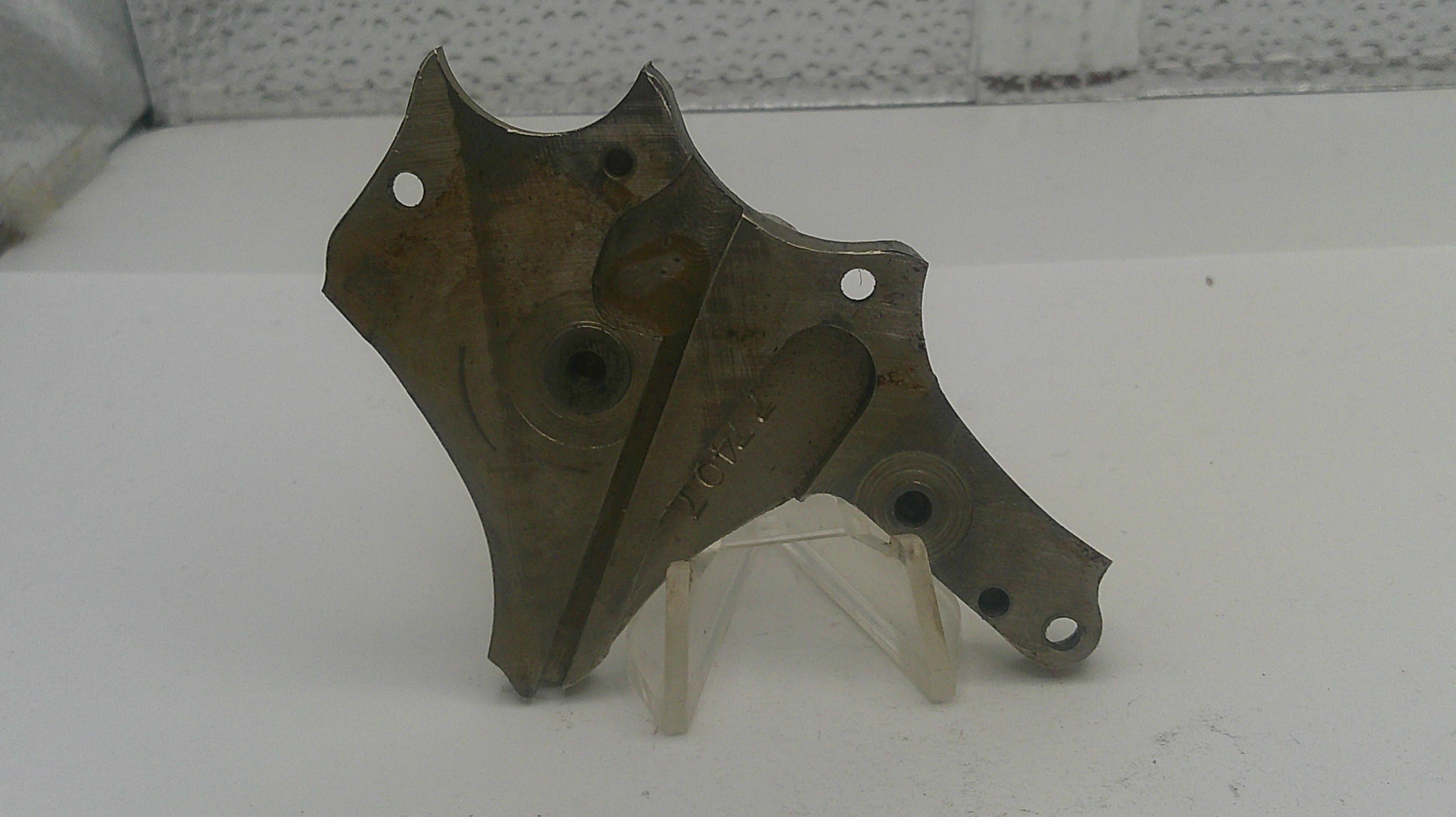 Metal mechanical component on a white surface with a textured wall background