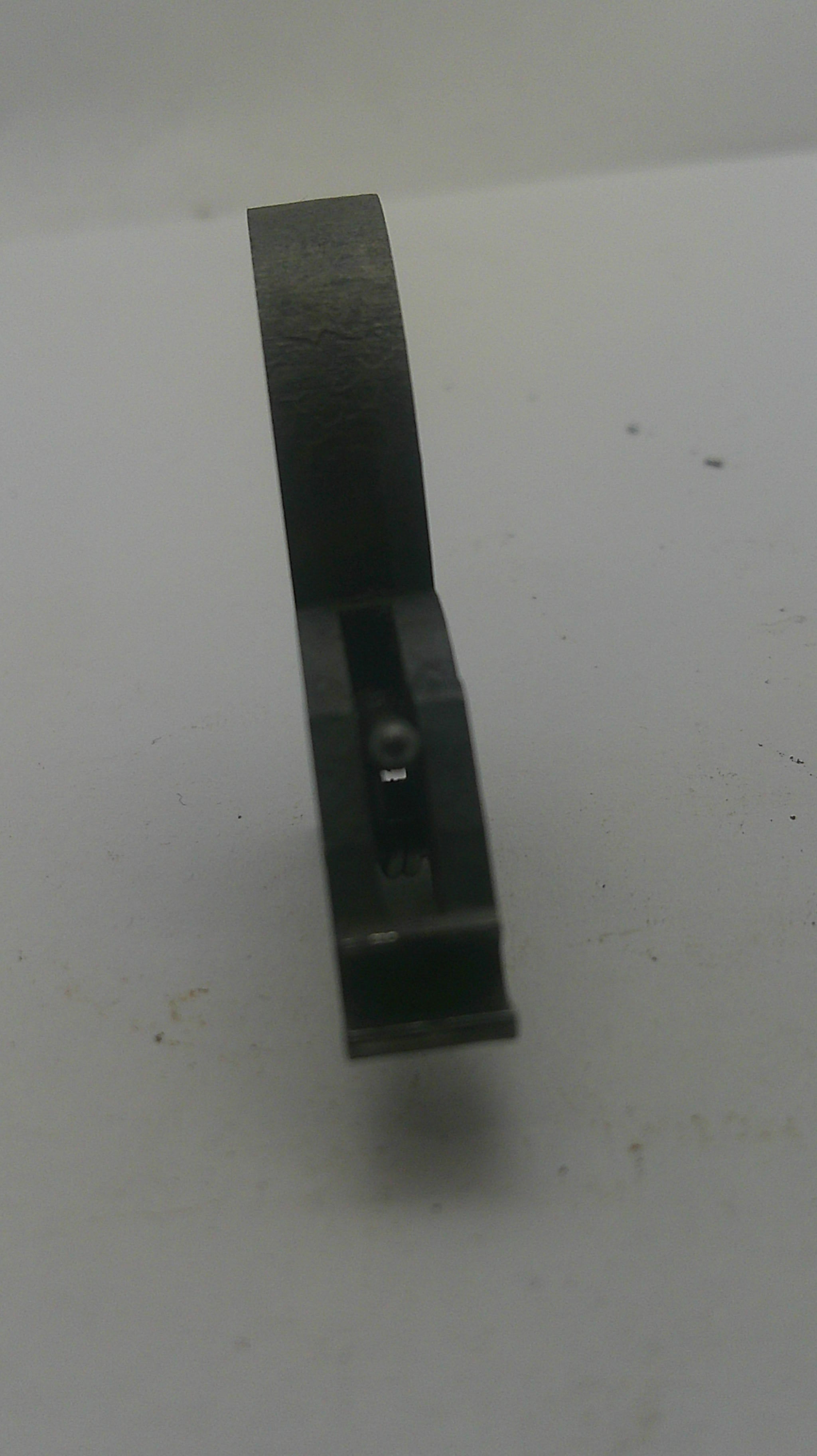A dark metal flathead chisel with a black handle, photographed against a plain off-white background.