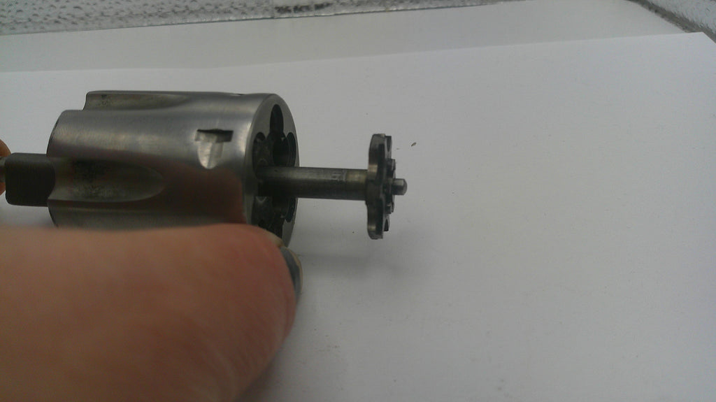 Metal gear or motor component held by a hand on a white background