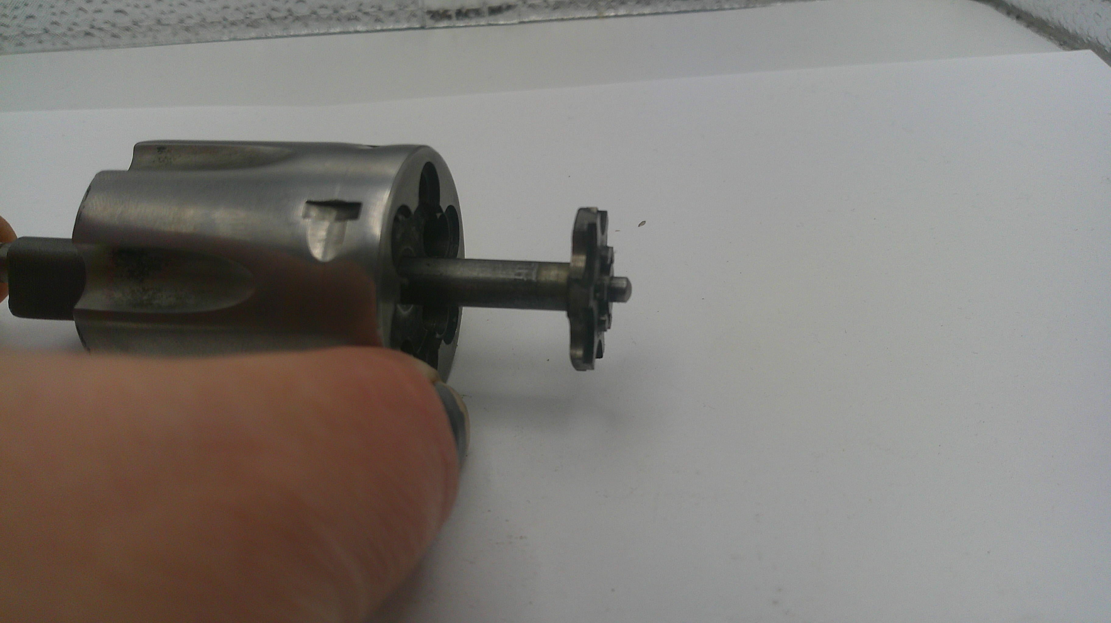 Metal gear or motor component held by a hand on a white background