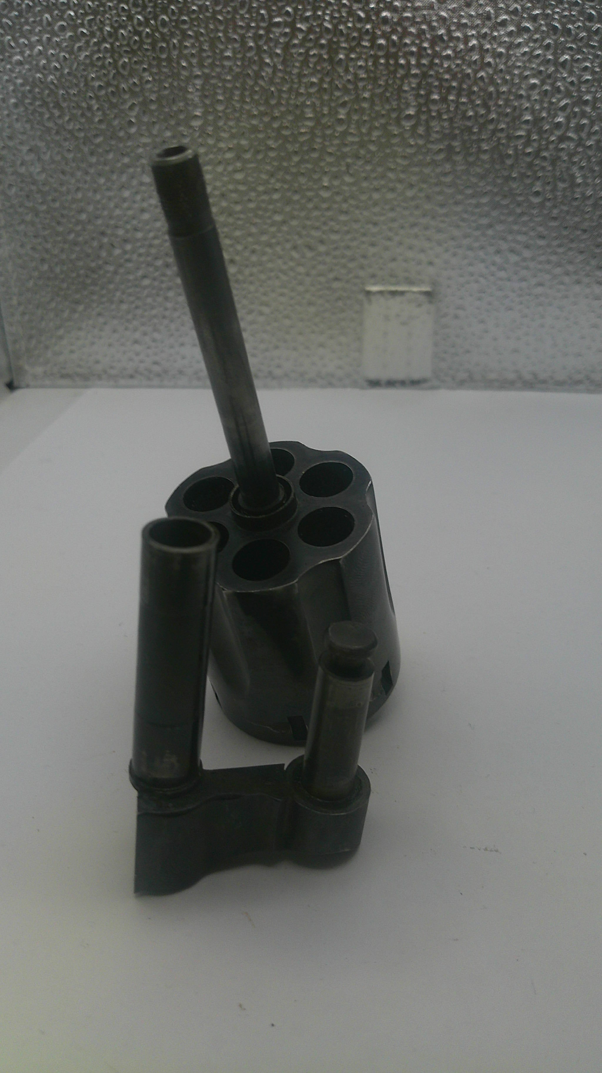 Black metal pipe fitting on a white surface with a textured gray background