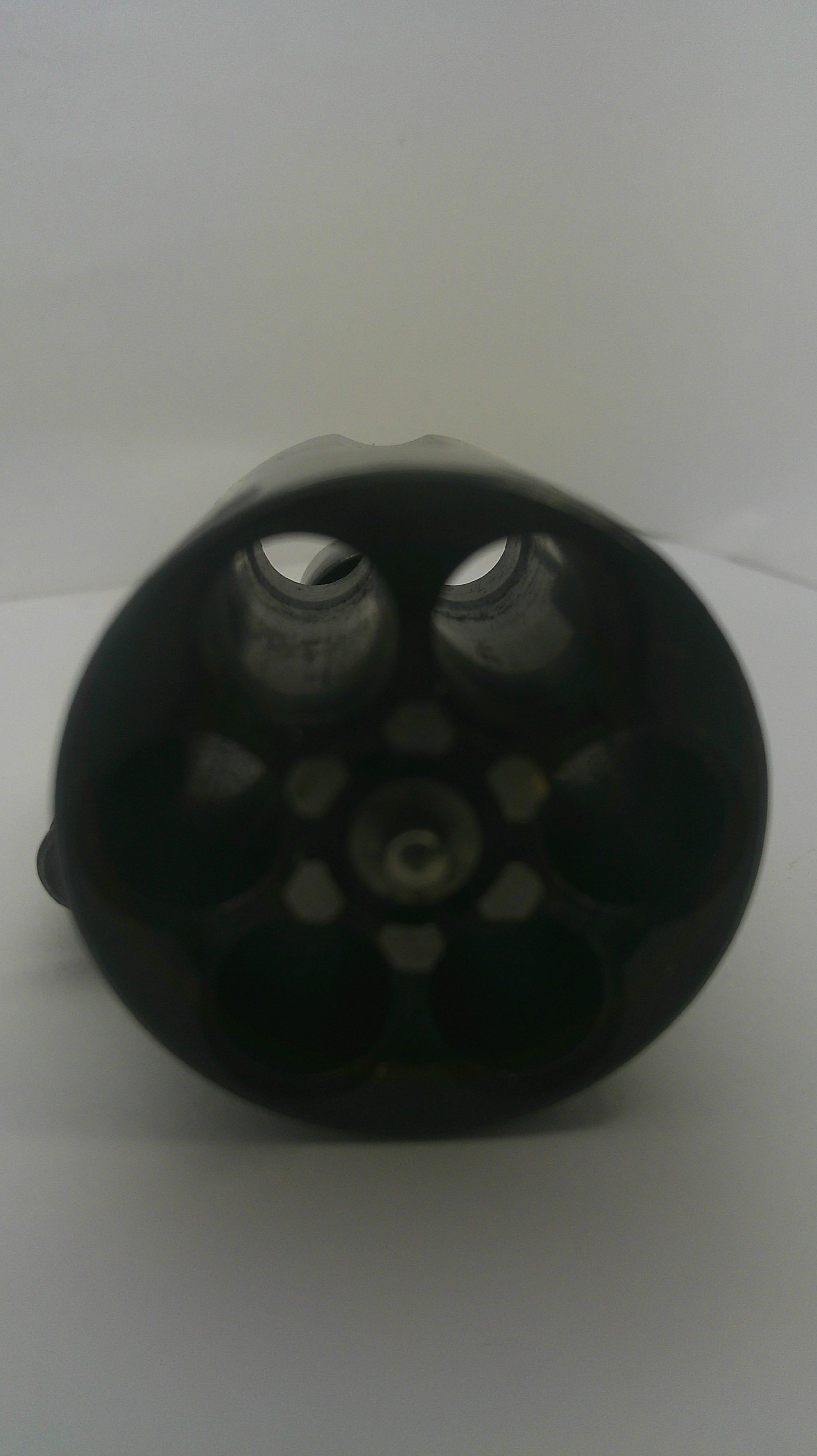 A black plastic revolver cylinder holder or magazine base viewed from above on a plain white background.