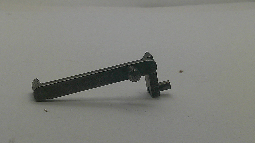 A small dark metal watch or clock pinion and wheel component with a central screw, photographed on a plain light background.