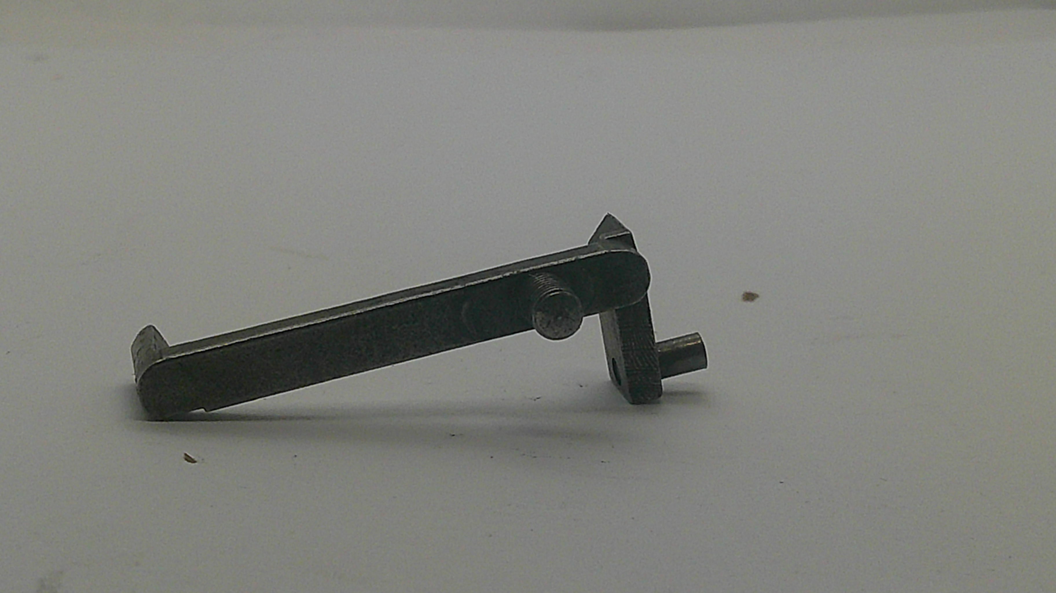 A small dark metal watch or clock pinion and wheel component with a central screw, photographed on a plain light background.