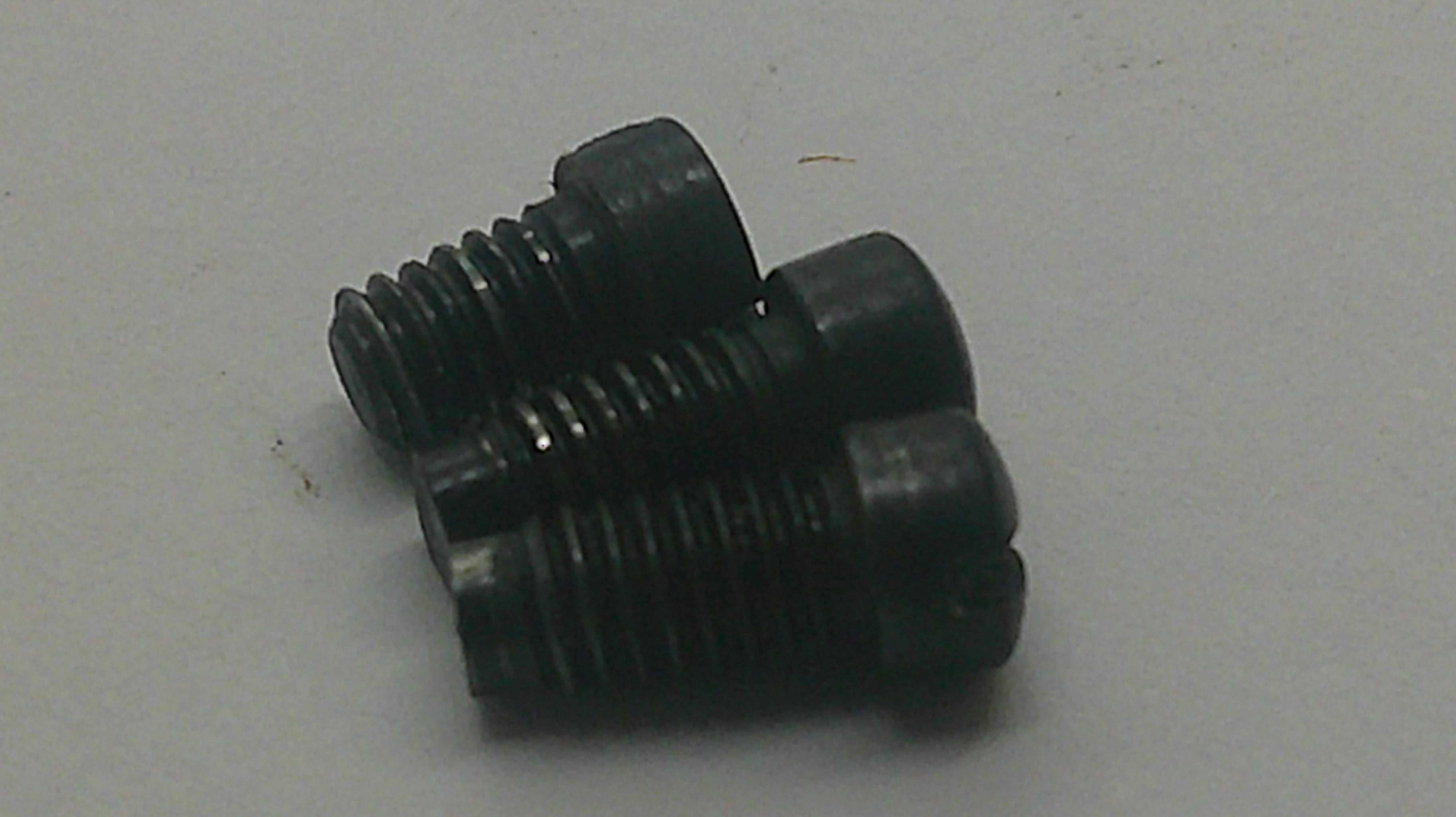 Three black metal threaded screws with countersunk heads, arranged on a plain light gray surface.