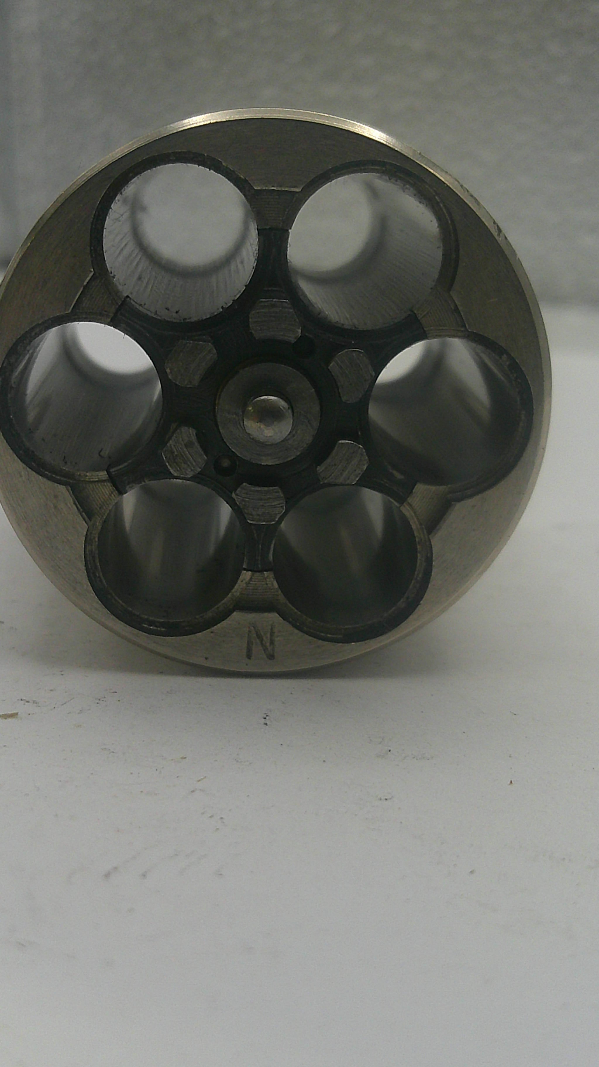 Metallic cylindrical component with multiple holes on a white background