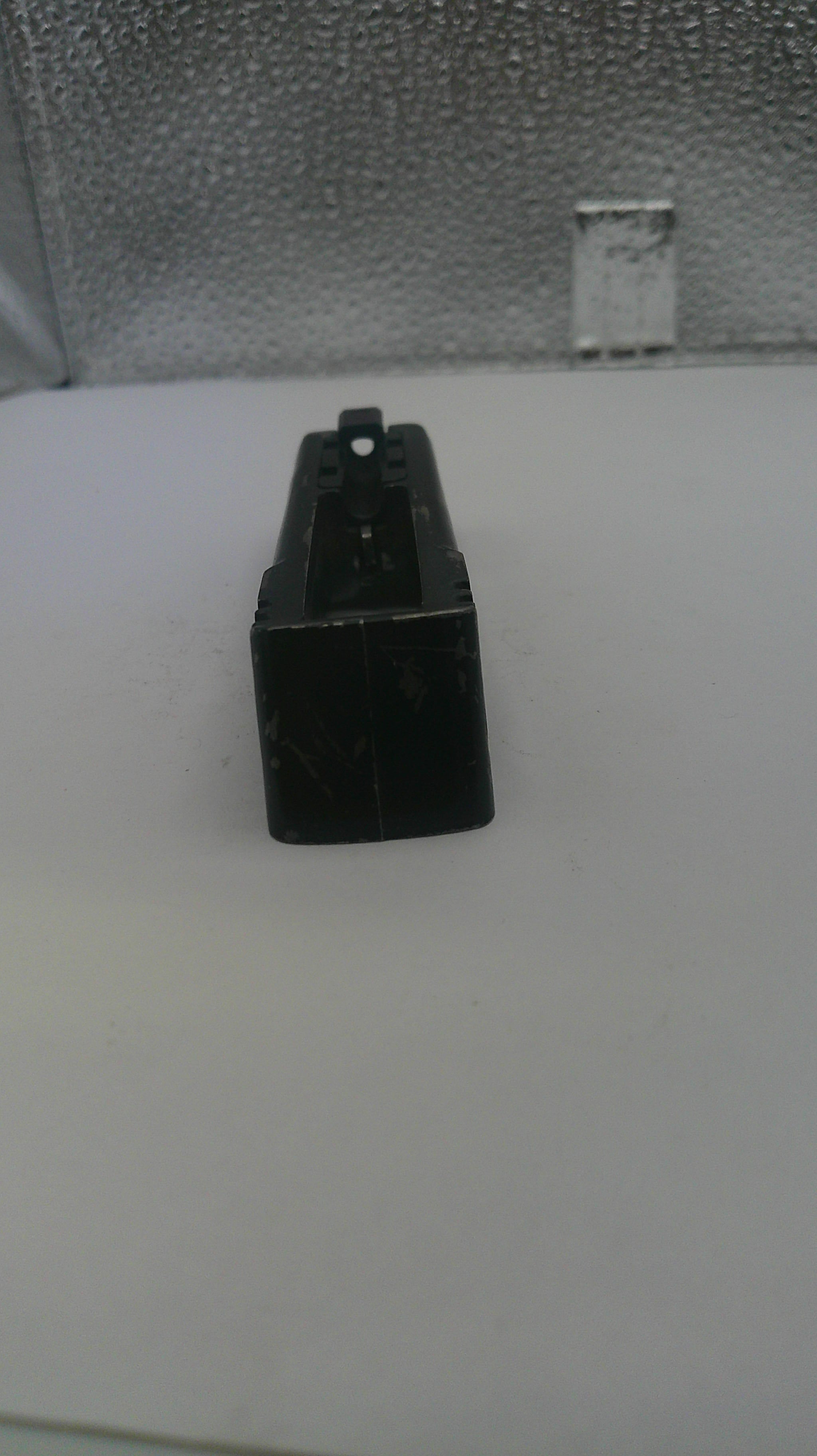 Black rectangular object on a white surface with a textured gray background