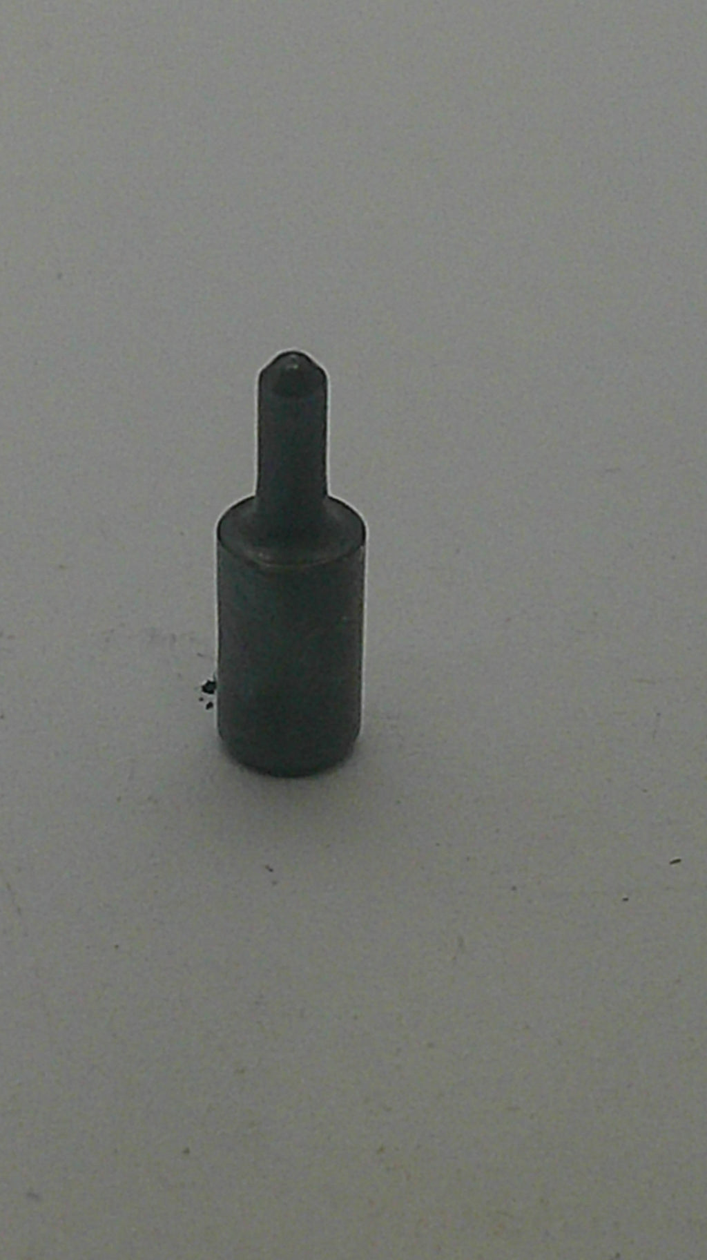 A small dark metal cylindrical tool or hardware piece with a pointed shaft, shown against a plain light gray background.