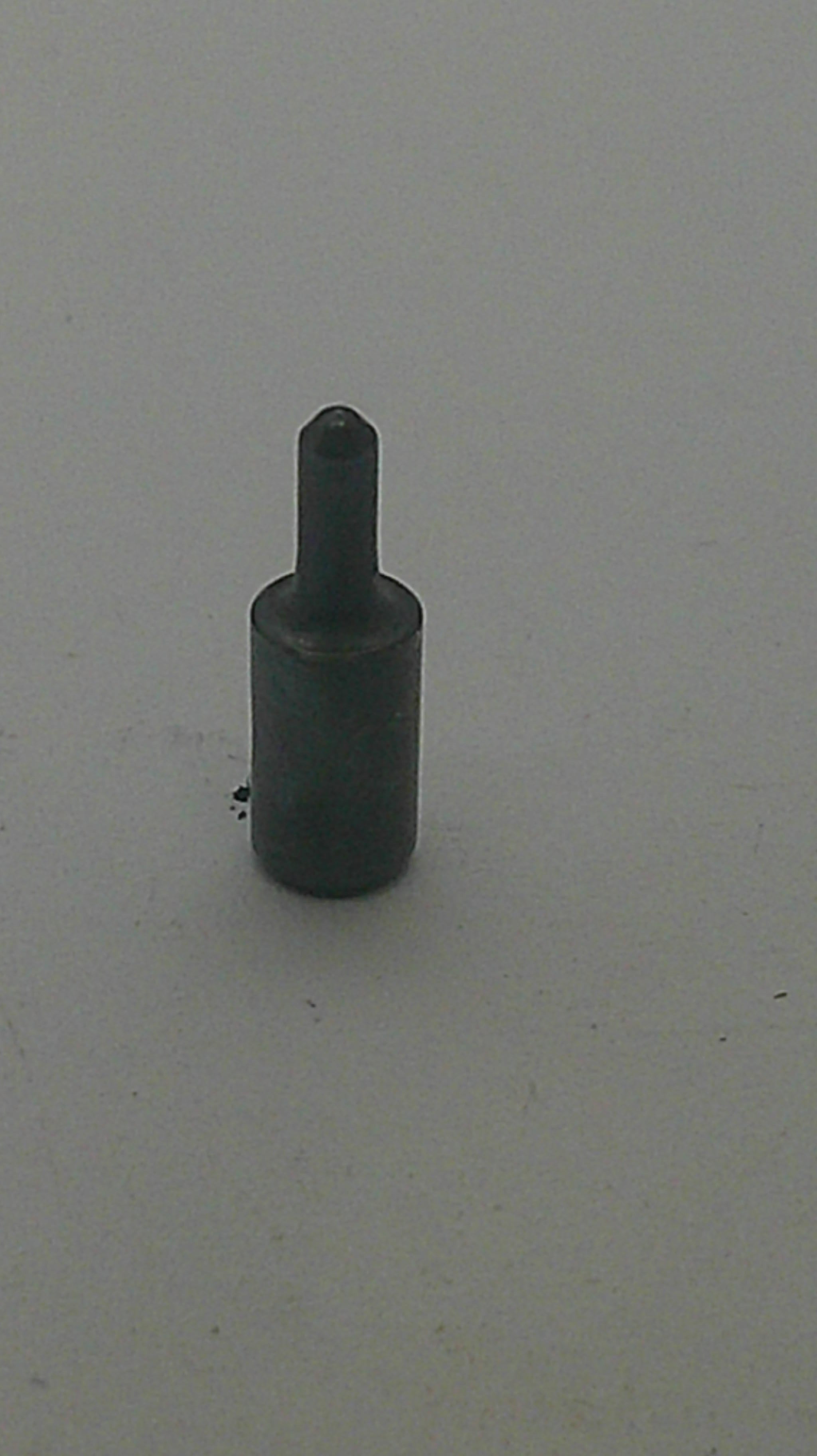 A small dark metal cylindrical tool or hardware piece with a pointed shaft, shown against a plain light gray background.